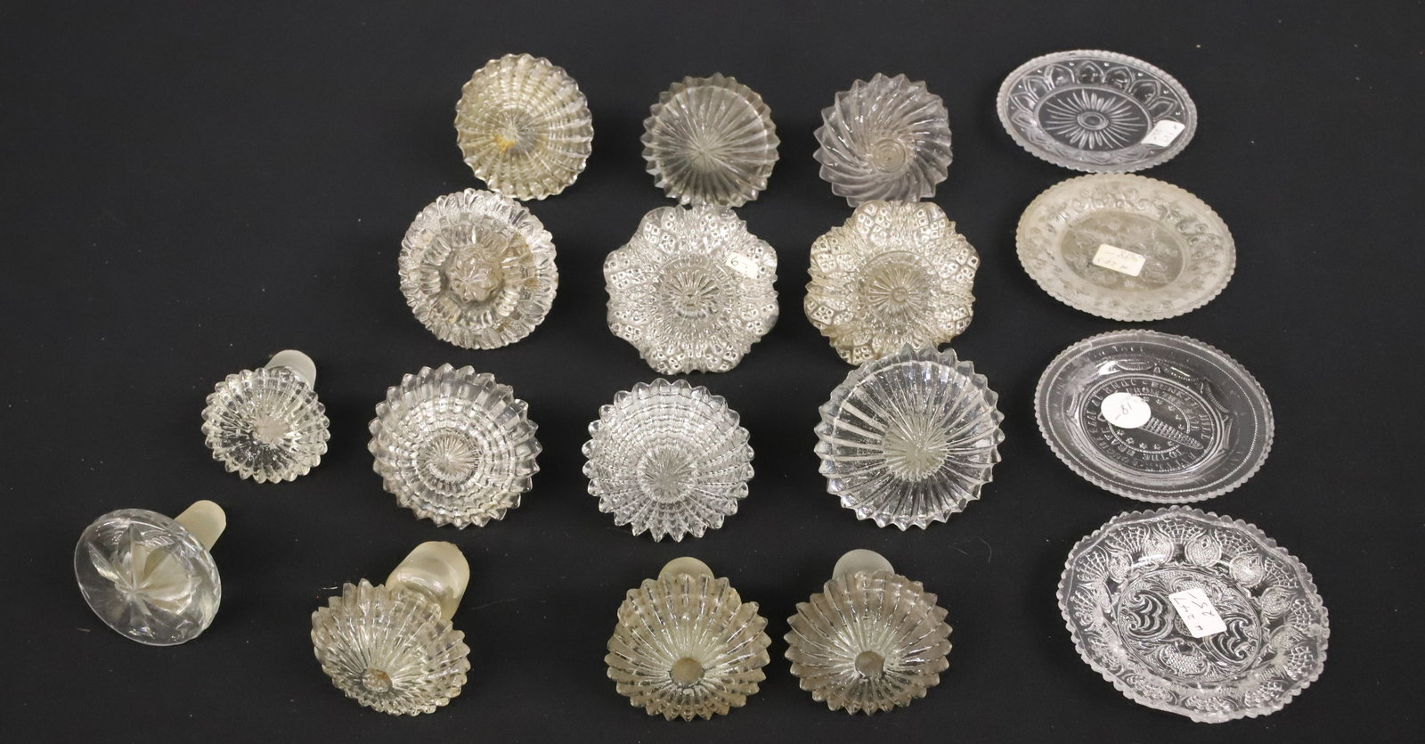 LOT OF ANTIQUE GLASS STOPPERS AND CUP PLATES: VARIETY OF SIZES AND STYLES FOR DECANTERS, CRUETS AND MORE. LARGEST 2 1/2" X 2 3/4" L. PLEASE READ CAREFULLY - ITEMS MUST BE PAID FOR THROUGH LIVE AUCTIONEERS OR WITH CASH OR CHECK IN PERSON - Terms f