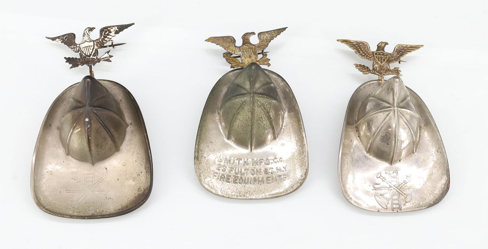 (3) METAL FIRE HELMET PINS: EAGLE PIN WITH FIRE HELMET HANGING FROM BOTTOM. ONE MRKD. "SMITH MFG. CO. 123 FULTON ST. NY FIRE EQUIPMENTS". 3" TOTAL LENGTH. PLEASE READ CAREFULLY - ITEMS MUST BE PAID FOR THROUGH LIVE