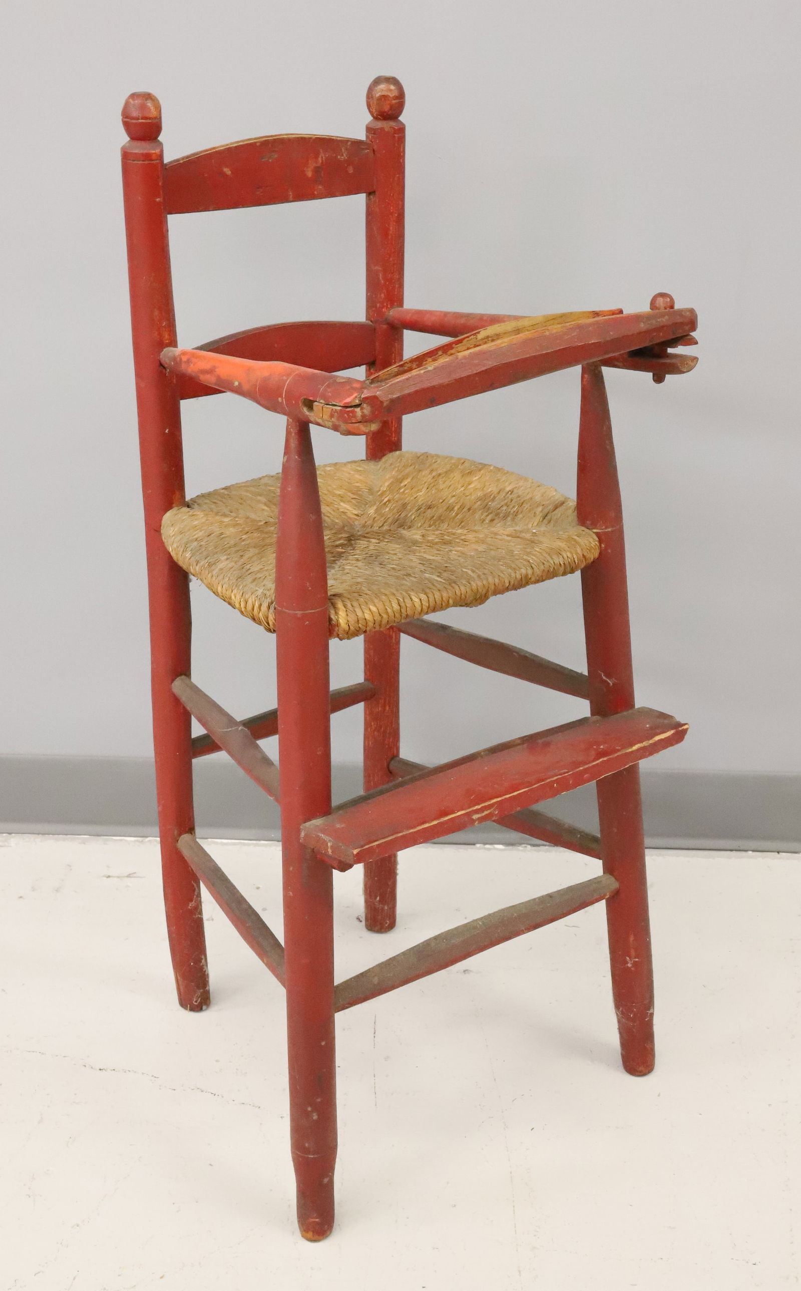 PAINTED WOODEN HIGH CHAIR: RED PAINTED SURFACE. RUSH SEAT. 34" X 13 1/4" X 14 1/2". PLEASE READ CAREFULLY - ITEMS MUST BE PAID FOR THROUGH LIVE AUCTIONEERS OR WITH CASH OR CHECK IN PERSON - Terms for Purchasing and
