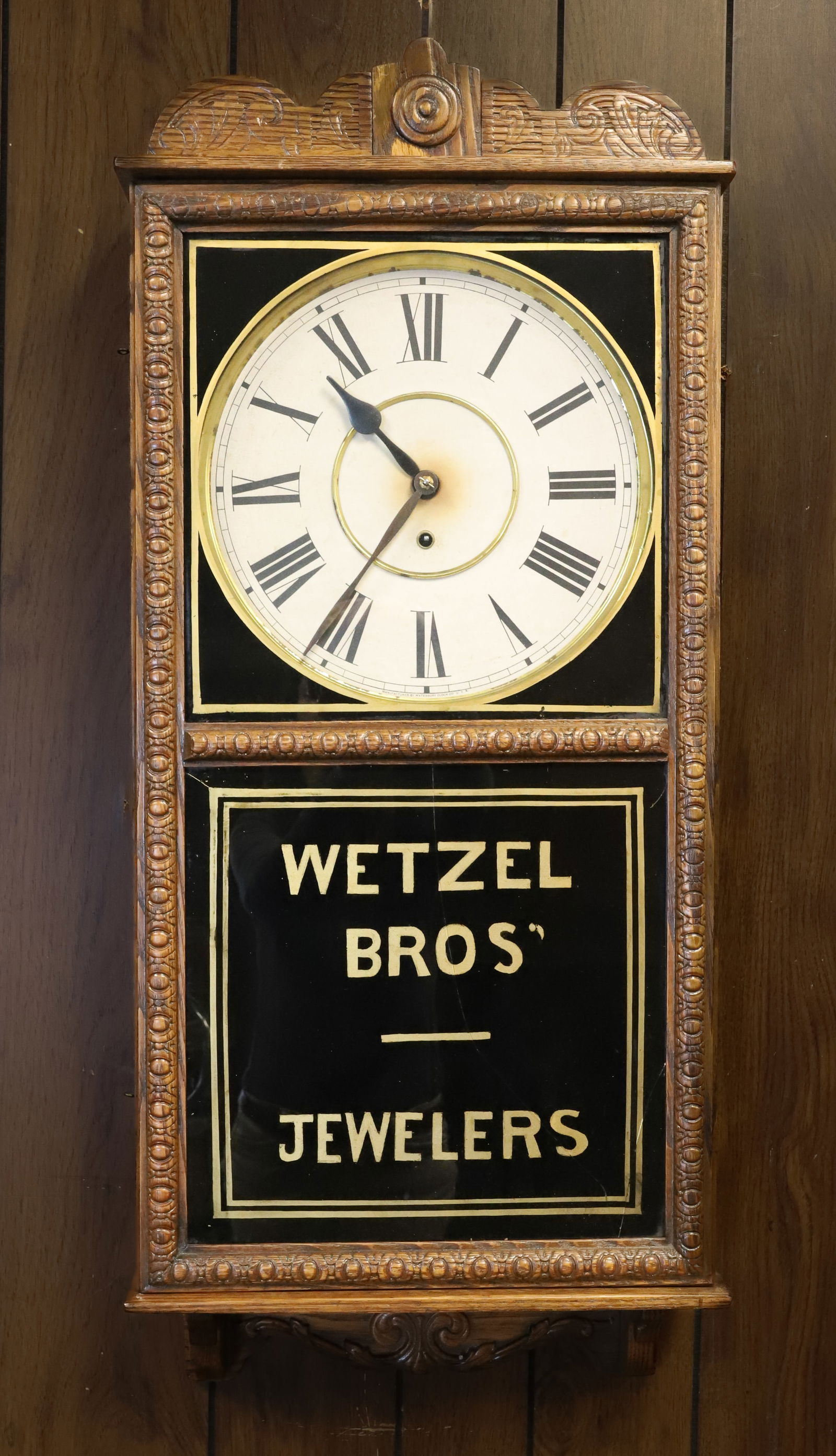 WETZEL BROS' JEWELERS ADVERTISING CLOCK: WATERBURY CLOCK IN OAK CASE WITH PAPER DIAL. KEY AND PENDULUM. 37" X 16" X 5". PLEASE READ CAREFULLY - ITEMS MUST BE PAID FOR THROUGH LIVE AUCTIONEERS OR WITH CASH OR CHECK IN PERSON - Terms for