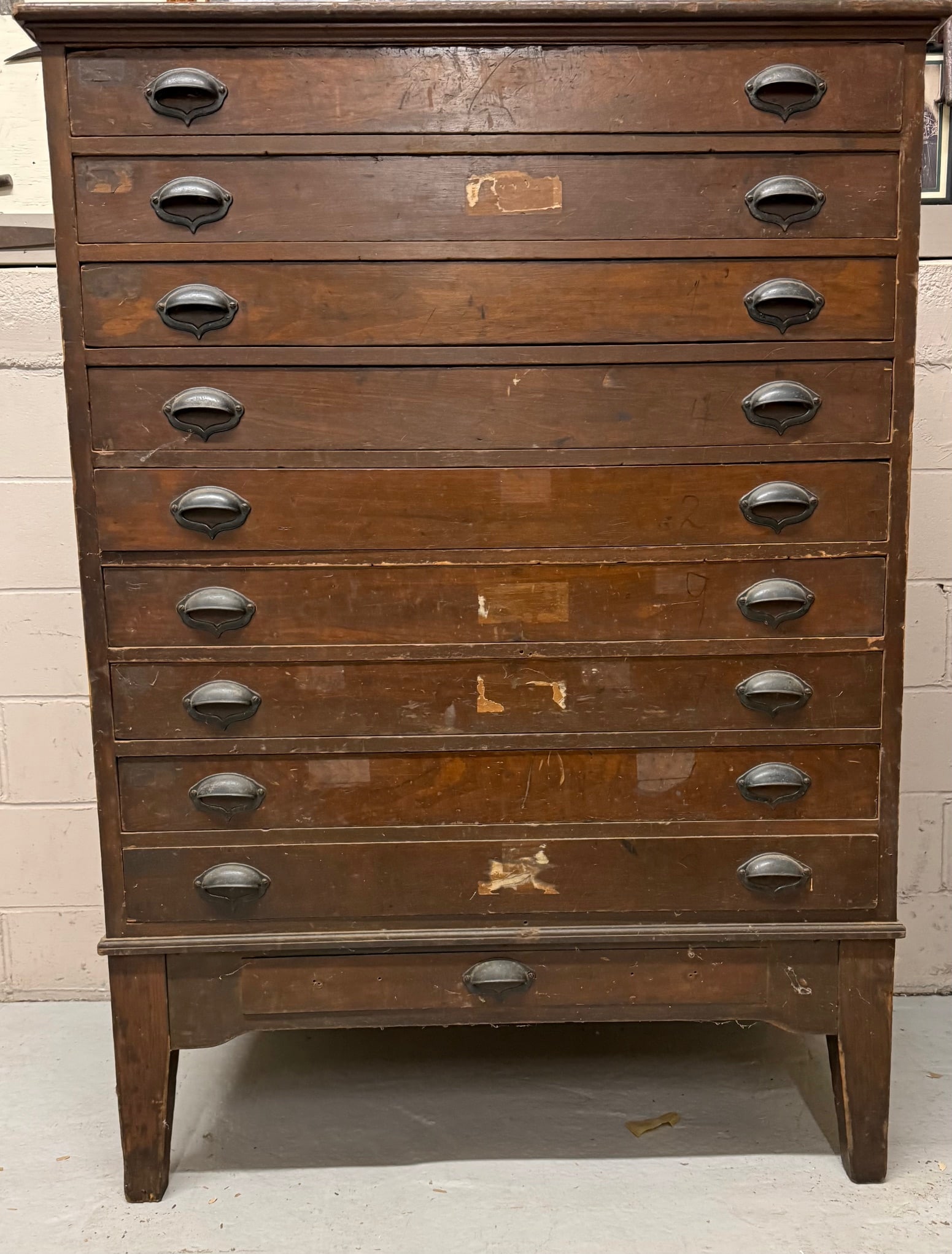 ANTIQUE OAK STORAGE CABINET: NINE DRAWERS OVER SMALLER SINGLE DRAWER. CAST IRON HARDWARE. PANELED ENDS. 60" X 43 1/2" X 29 1/2". DRAWERS MEASURE 39 1/2" X 4" X 25 1/2" DEEP. HEAVY IN WEIGHT.
