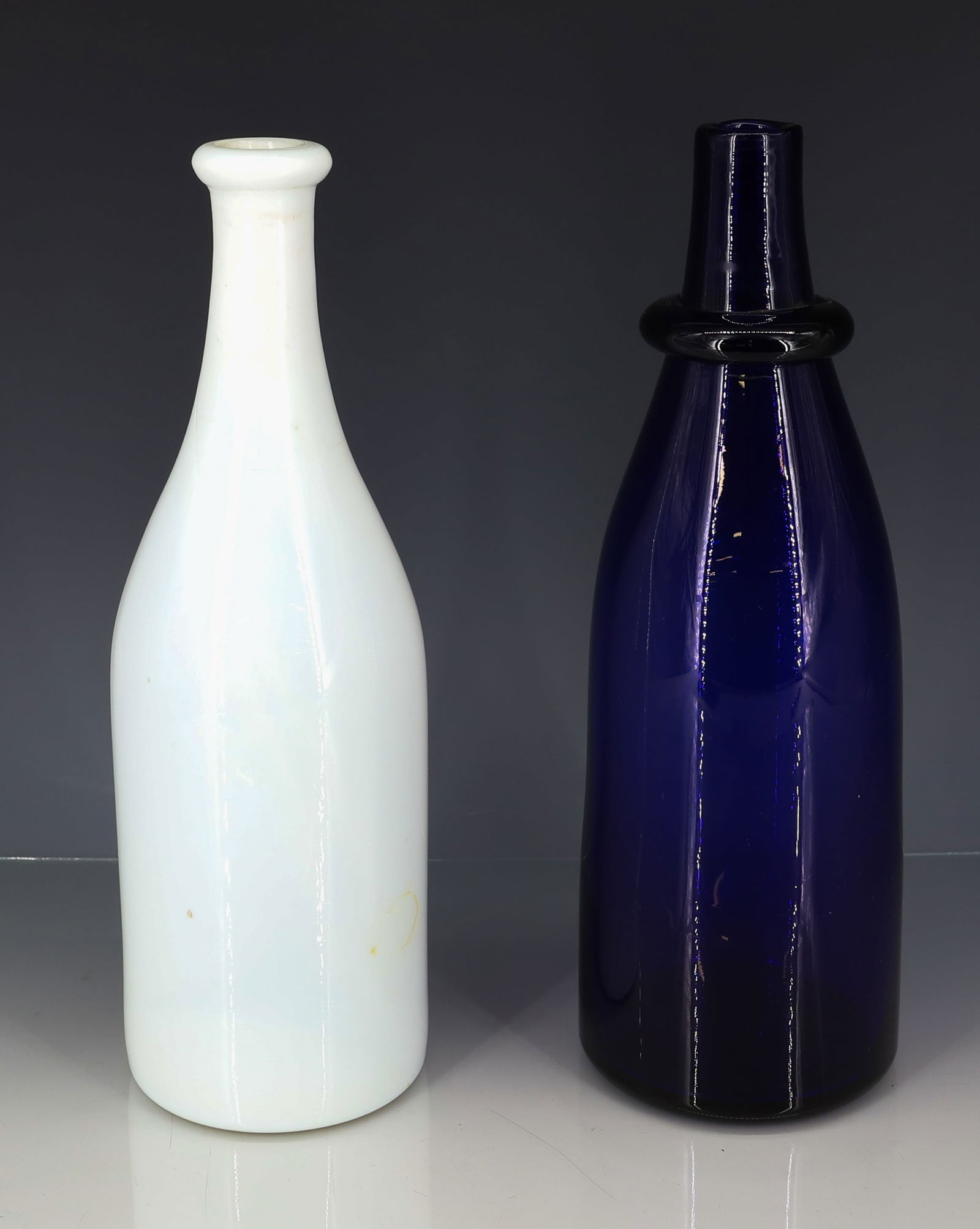 EARLY BLOWN GLASS BAR BOTTLES: COBALT BLUE WITH GRIP RING AND POLISHED PONTIL, MILK GLASS BLOWN WITH ROUGH PONTIL 10 3/4"H, 10 1/2"H PLEASE READ CAREFULLY - ITEMS MUST BE PAID FOR THROUGH LIVE AUCTIONEERS OR WITH CASH OR CHECK IN P