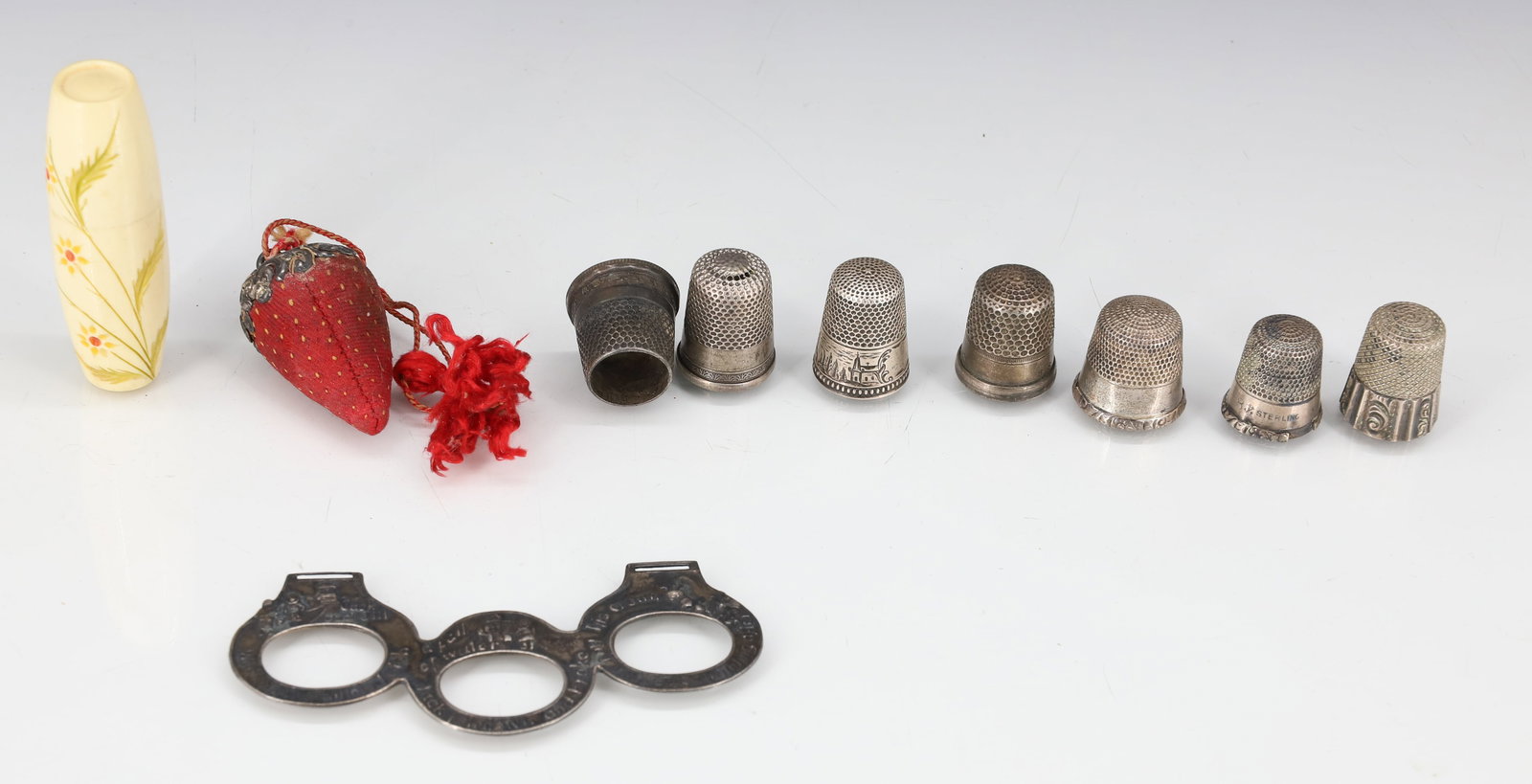 VICTORIAN STERLING SILVER THIMBLES, STRAWBERRY LOT: STERLING TOPPED STRAWBERRY NEEDLE CLEANER, (7) THIMBLES ONE WITH ENGRAVED VILLAGE, LIGHTHOUSES AND SHIP, STERLING INFANT TOY HOLDER ( PLAY TOYS HELD BY CORD/RIBBONS) AND 1930S BAKELITE SEWING KIT LARG