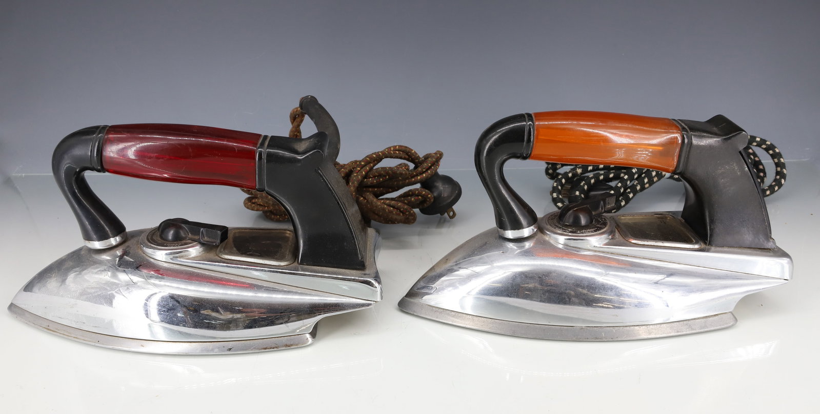 (2) AMERICAN BEAUTY ELECTRIC IRONS: RED AND AMBER HANDLES. PLEASE READ CAREFULLY - ITEMS MUST BE PAID FOR THROUGH LIVE AUCTIONEERS OR WITH CASH OR CHECK IN PERSON - Terms for Purchasing and Shipping of Auction Items. Please read