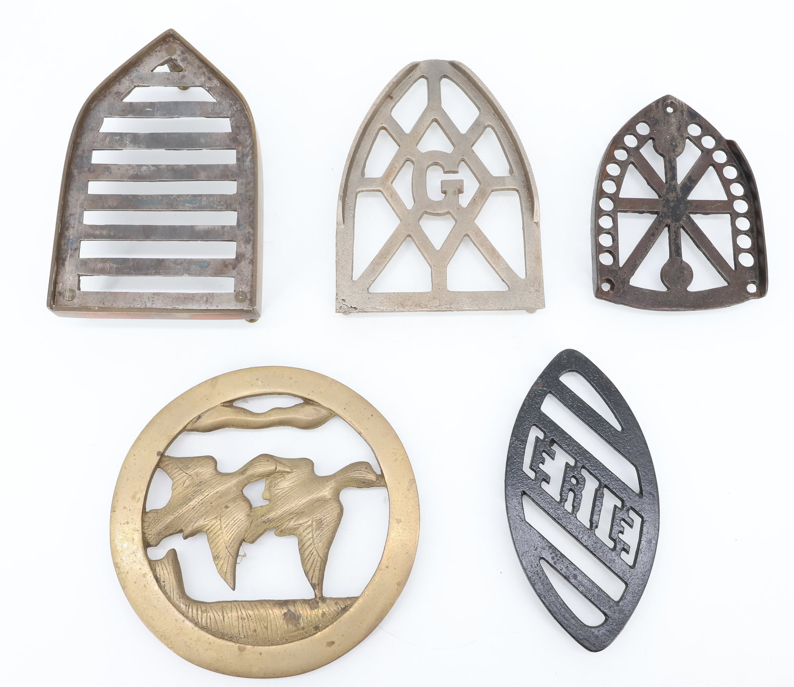 LOT OF ANTIQUE PRESSING IRON TRIVETS: (5) INCLUDING: SMARTS BROCKVILLE WITH "G", SMART LIMITED CANADA, ERIE DOUBLE-POINT, BRASS SLUG IRON TRIVET AND ROUND BRASS TRIVET WITH GEESE. PLEASE READ CAREFULLY - ITEMS MUST BE PAID FOR THROUGH