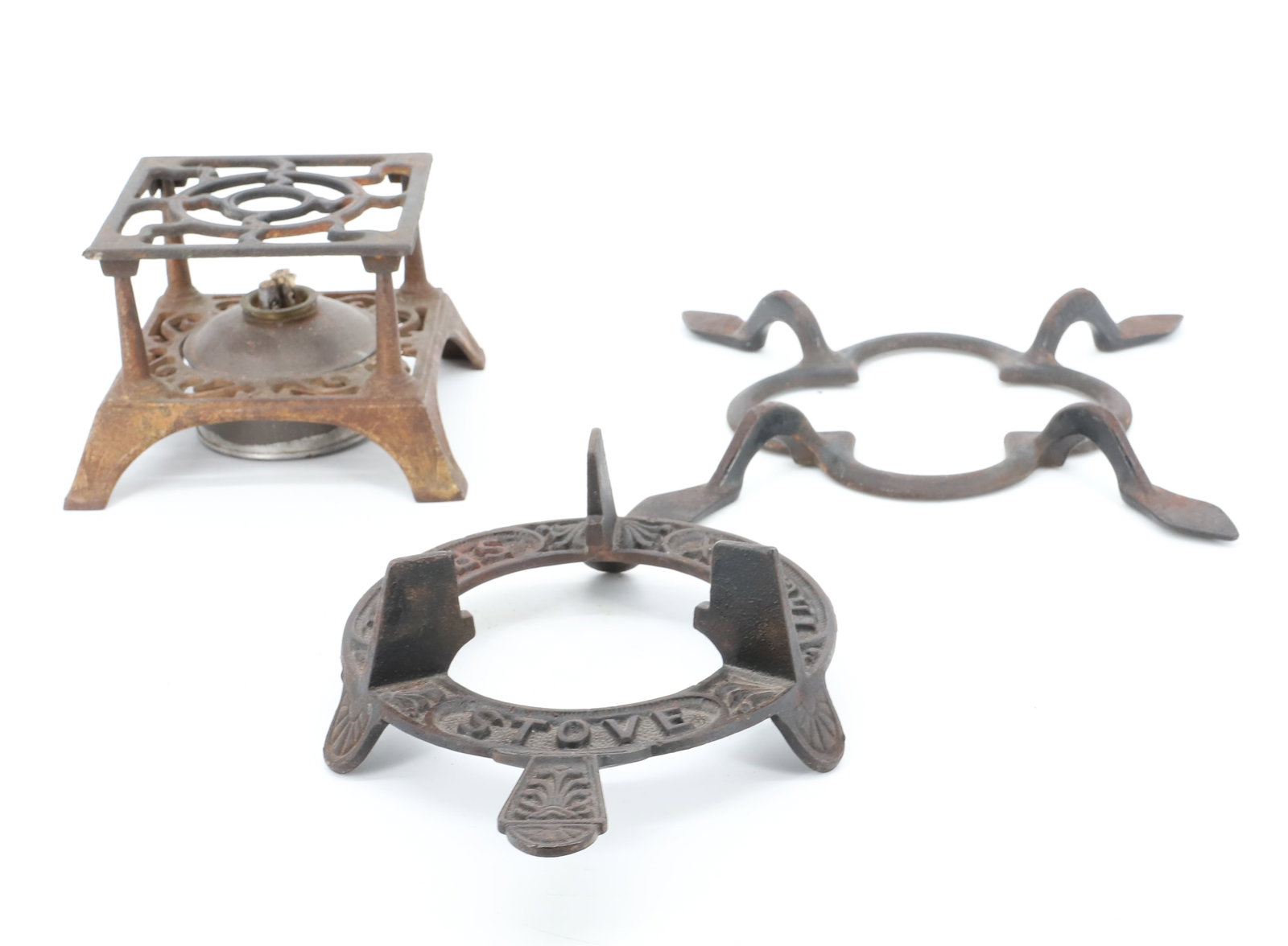 LOT OF (2) TRIVETS AND HEATER: PHOENIX SPIRIT STOVE TRIPOD TRIVET 8" L. UNUSUAL FOUR FOOTED TRIVET 11 1/2" D. CAST IRON HEATER WITH TIN FUEL RESERVOIR. PLEASE READ CAREFULLY - ITEMS MUST BE PAID FOR THROUGH LIVE AUCTIONEERS OR