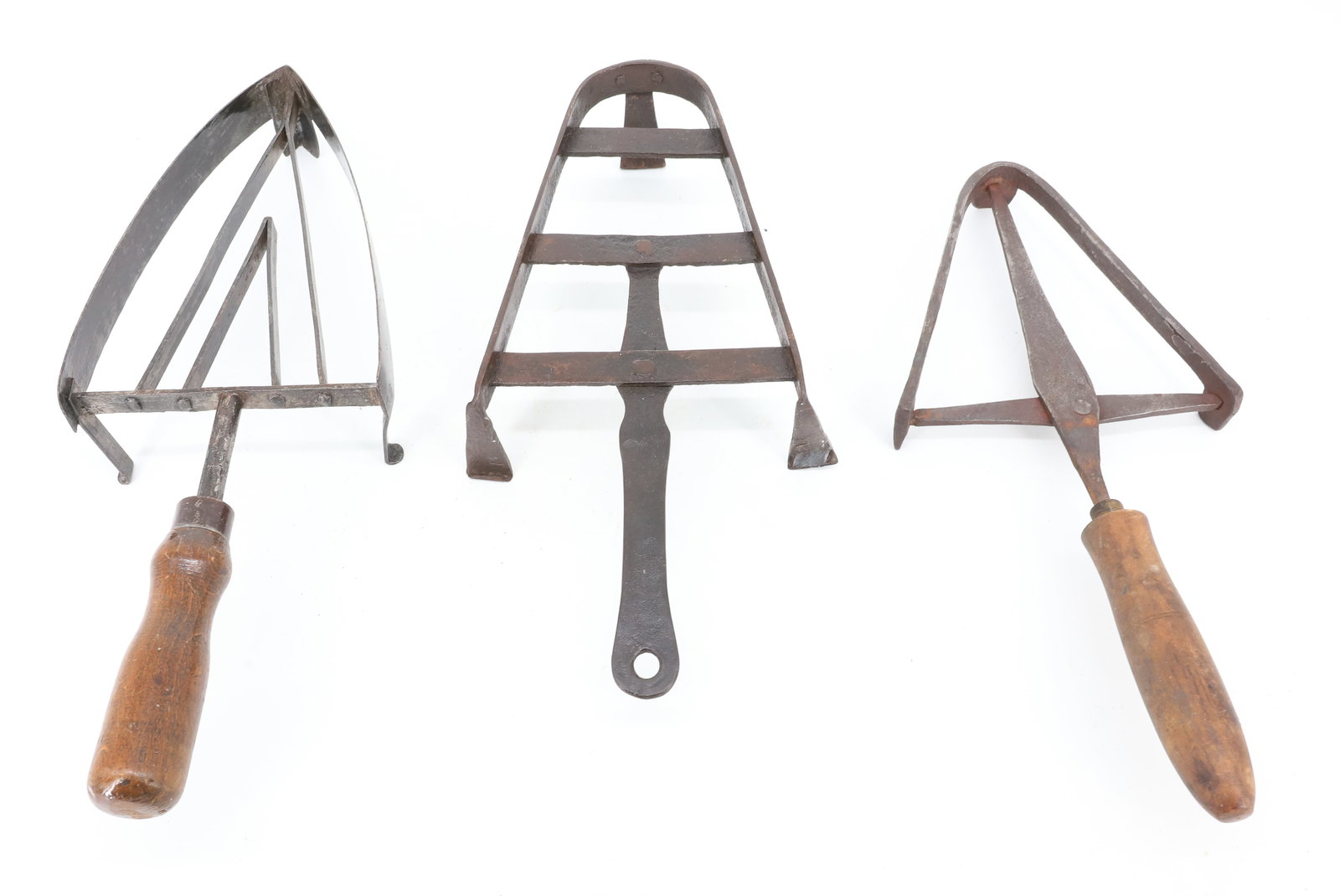 (3) ANTIQUE FOOTED TRIVETS: TWO WITH WOODEN HAND GRIPS. 13 1/4" TO 15" LENGTHS. PLEASE READ CAREFULLY - ITEMS MUST BE PAID FOR THROUGH LIVE AUCTIONEERS OR WITH CASH OR CHECK IN PERSON - Terms for Purchasing and Shipping of