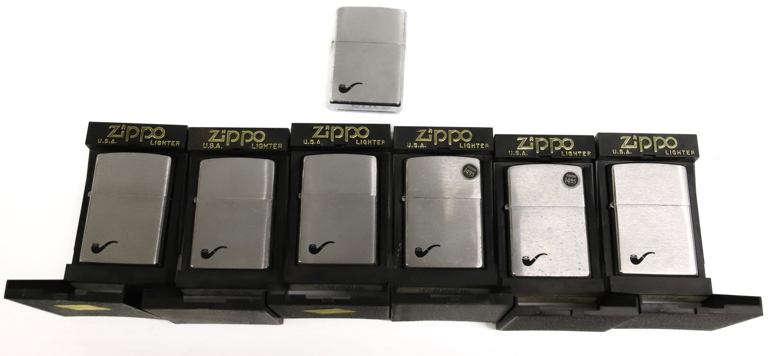 (7) Zippo Lighters, New in Box: Smoking Pipe motif. One does not have box. PLEASE READ CAREFULLY - ITEMS MUST BE PAID FOR THROUGH LIVE AUCTIONEERS OR WITH CASH OR CHECK IN PERSON - Terms for Purchasing and Shipping of Auction