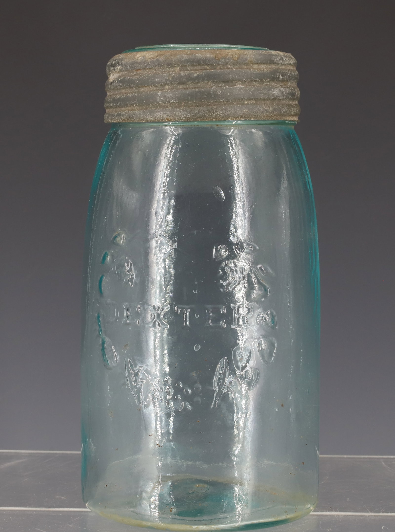 19TH CENTURY DEXTER FRUIT JAR: AQUA JAR WITH EMBOSSED LETTERING, SURROUNDED BY CIRCLE OF FRUIT, MATCHING DEXTER IMPROVED GLASS LID, PATENT 1865 WITH ZINC BAND - 7" H PLEASE READ CAREFULLY - ITEMS MUST BE PAID FOR THROUGH LIVE