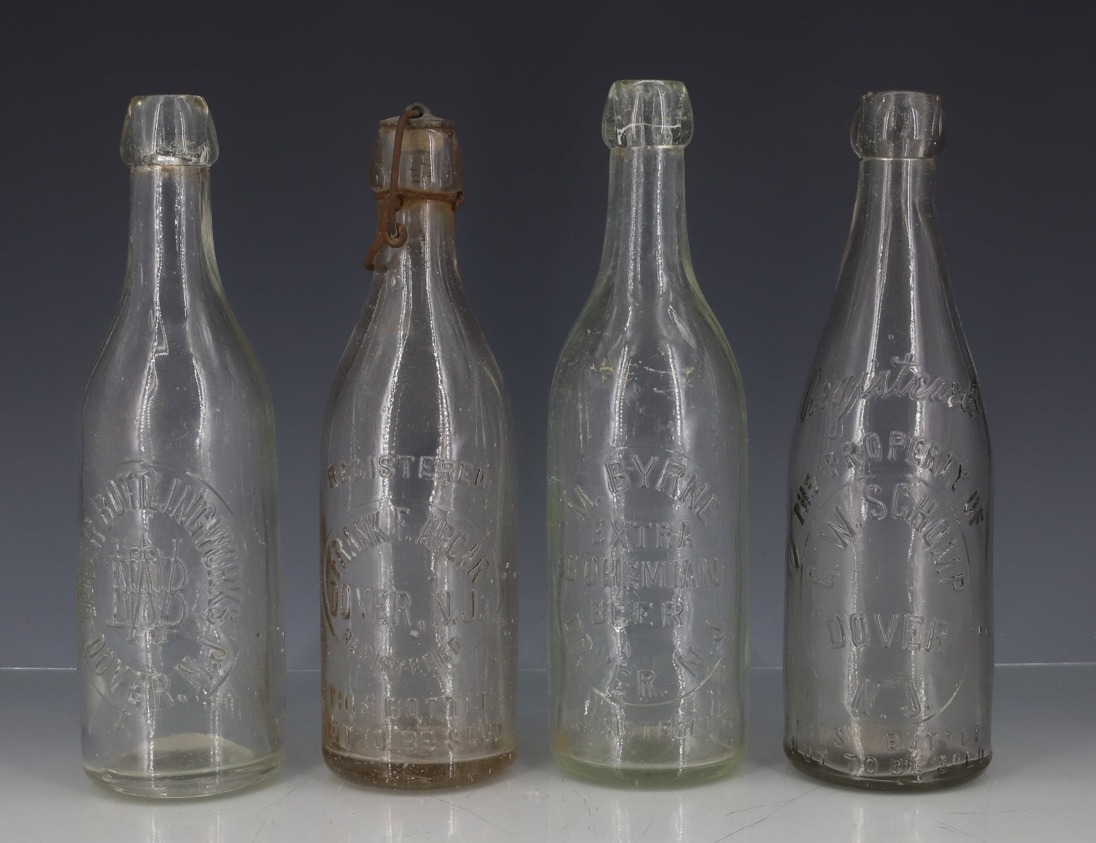(4) DOVER, NJ BOTTLES: EMBOSSED CLEAR BOTTLES INCLUDING: M. BYRNE (EXTRA BOHEMIAN BEER). C.W. SCHOMP. DOVER BOTTLING WORKS. FRANK F. APGAR. 9" H. PLEASE READ CAREFULLY - ITEMS MUST BE PAID FOR THROUGH LIVE AUCTIONEERS OR