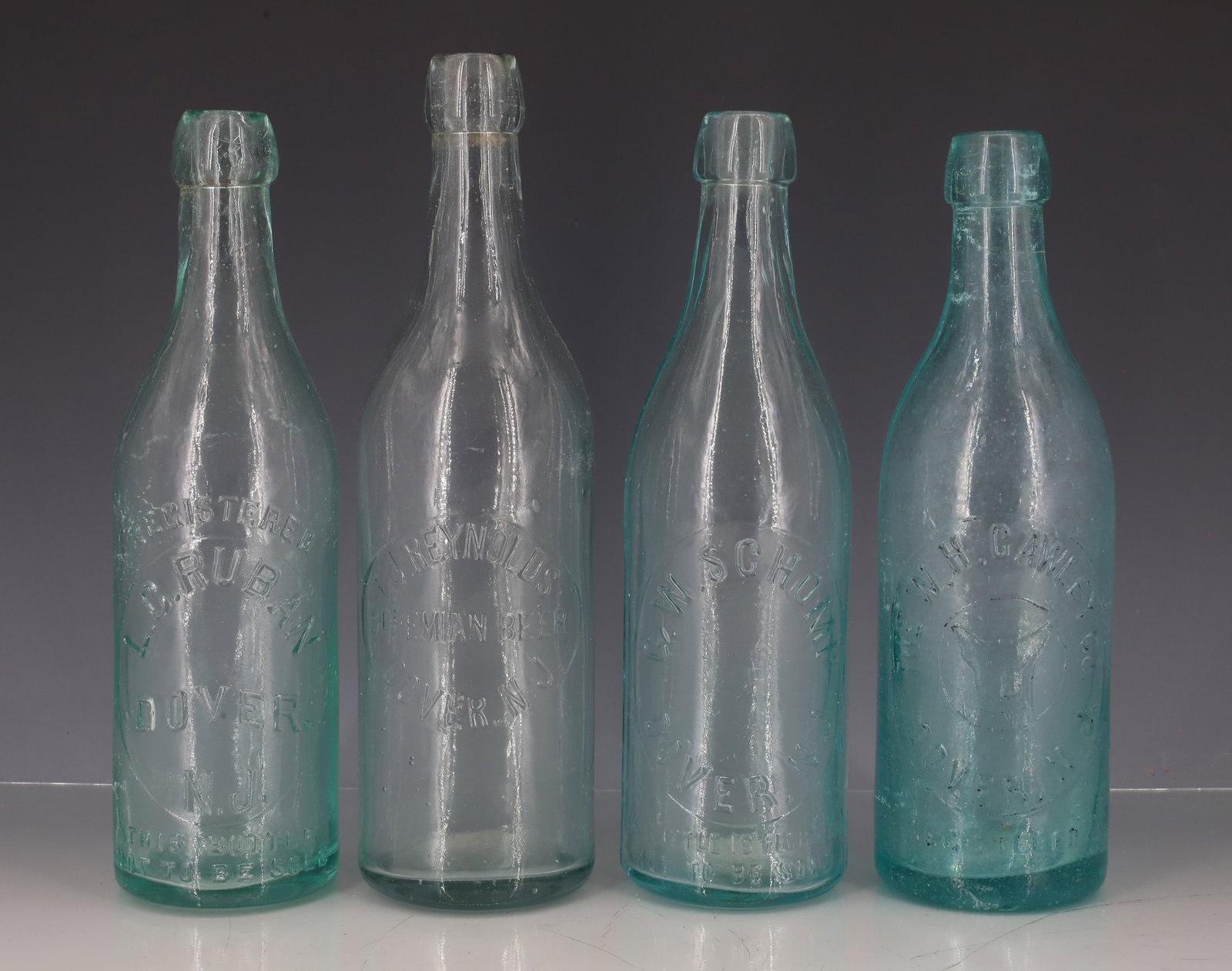 (4) AQUA DOVER, NJ BOTTLES: EMBOSSED INCLUDING: L.C. RUBAN. T.J. REYNOLDS. C.W. SCHOMP. THE W.H. CAWLEY CO. LARGEST 9 3/4" H. PLEASE READ CAREFULLY - ITEMS MUST BE PAID FOR THROUGH LIVE AUCTIONEERS OR WITH CASH OR CHECK IN