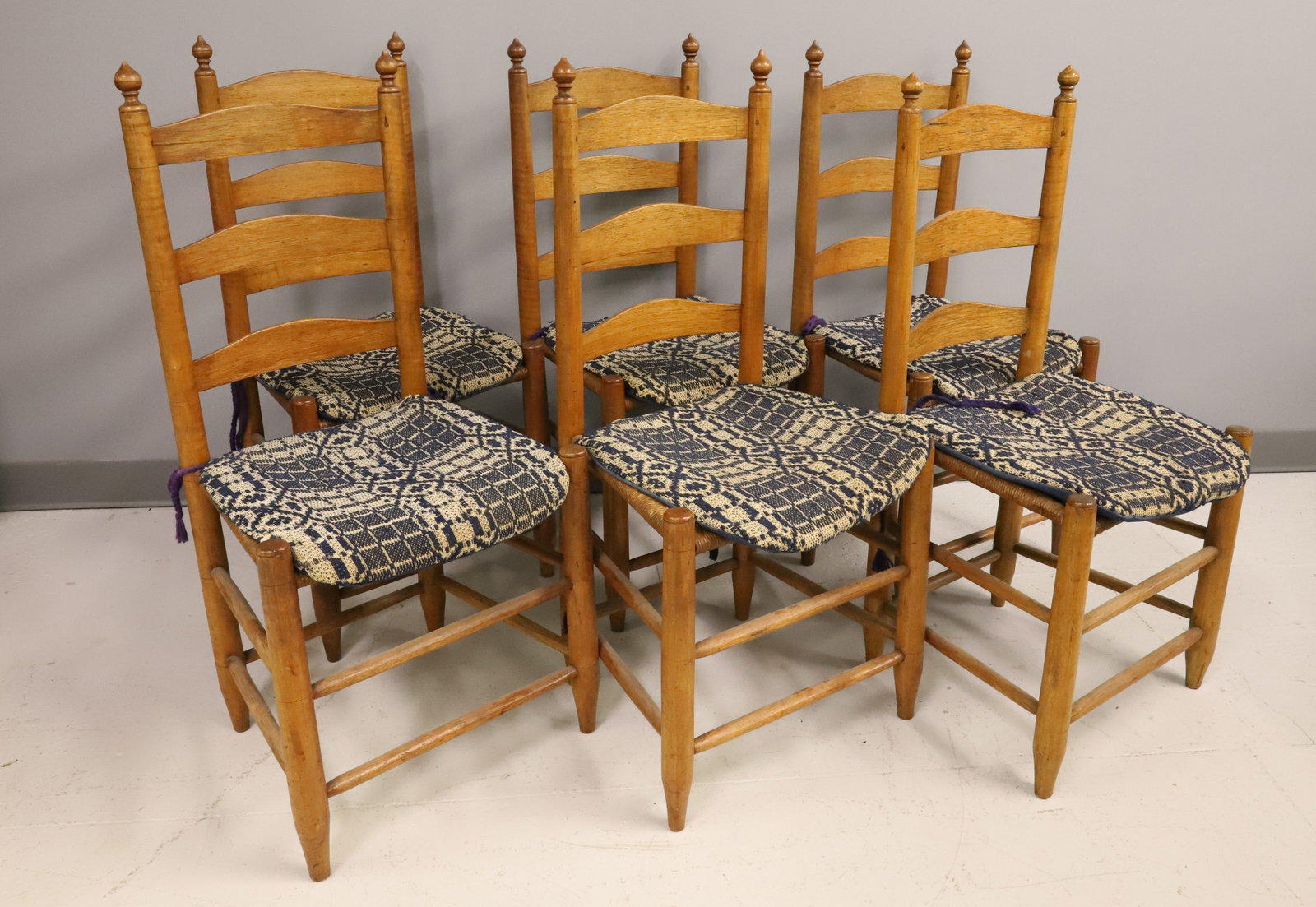 SET OF (6) LADDER BACK CHAIRS: MIXED WOOD WITH TIGER MAPLE, RUSH SEATS, AND ANTIQUE COVERLET SEAT PADS - 37" X 18" X 14" PLEASE READ CAREFULLY - ITEMS MUST BE PAID FOR THROUGH LIVE AUCTIONEERS OR WITH CASH OR CHECK IN PERSON -