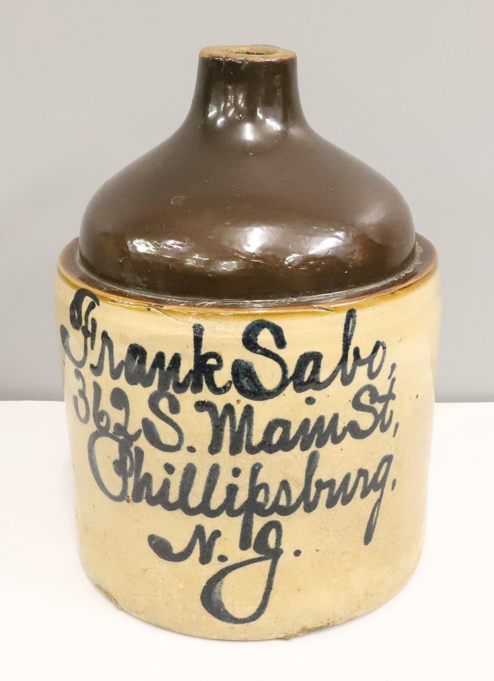 PHILLIPSBURG, NEW JERSEY SCRIPT ADVERTISING JUG: FRANK SABO, 362 S. MAIN ST, PHILLIPSBURG, NJ - BROWN GLAZE AT TOP, 12 1/2" H PLEASE READ CAREFULLY - ITEMS MUST BE PAID FOR THROUGH LIVE AUCTIONEERS OR WITH CASH OR CHECK IN PERSON - Terms for Purchas