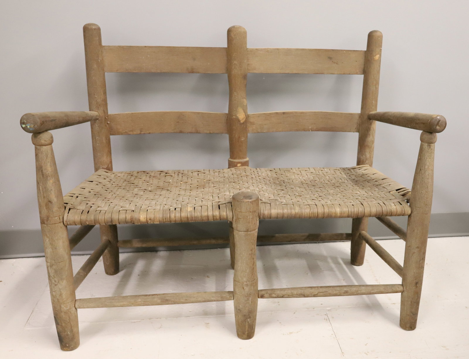 19TH C. WAGON SEAT: LADDERBACK WAGON SEAT WITH SIDE ARMS AND WOVEN SEATS. NATURAL FINISH. 30" X 37" X 15". PLEASE READ CAREFULLY - ITEMS MUST BE PAID FOR THROUGH LIVE AUCTIONEERS OR WITH CASH OR CHECK IN PERSON - Terms
