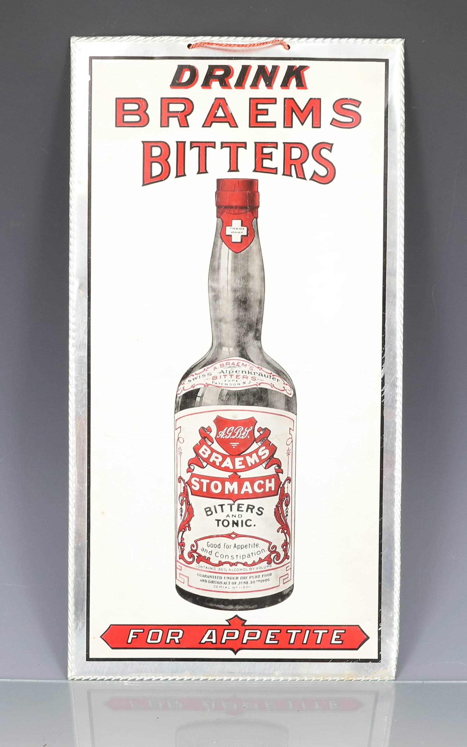BRAEMS BITTERS SIGN: METAL SIGN ON CARDBOARD "DRINK BRAEMS BITTERS FOR APPETITE" 13 1/2" X 7". PLEASE READ CAREFULLY - ITEMS MUST BE PAID FOR THROUGH LIVE AUCTIONEERS OR WITH CASH OR CHECK IN PERSON - Terms for