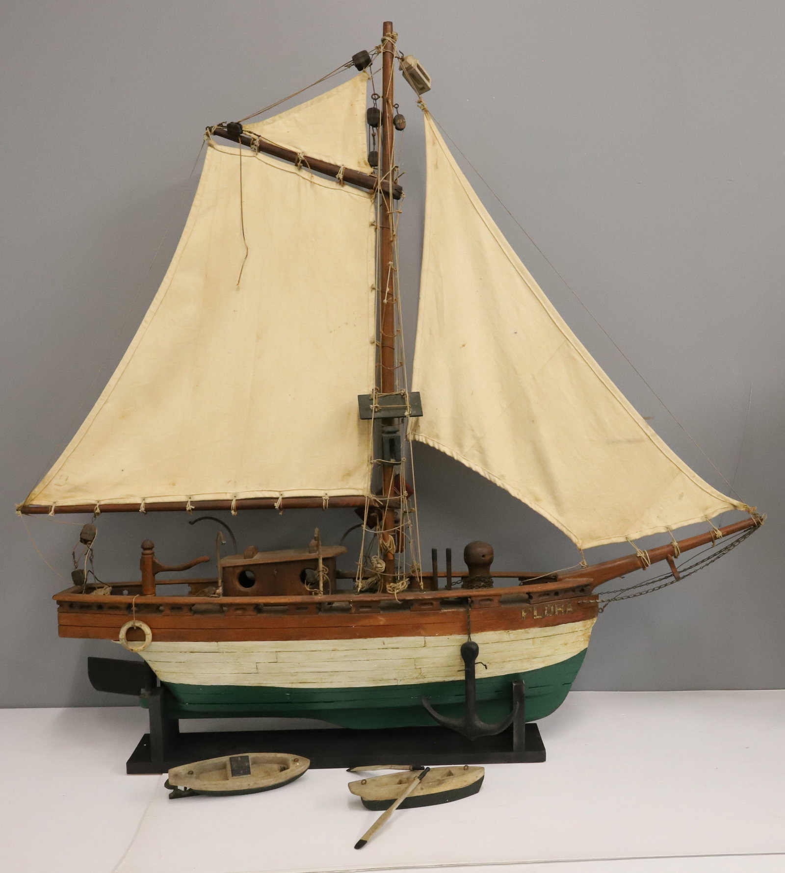 FOLK ARE MODEL SAILING SHIP: GREEN / WHITE PAINTED WOOD. "FLORA" BRASS LETTERS. CANVAS SAILS WITH RIGGING, ANCHOR, LIFEBOATS AND MORE. WOODEN DISPLAY STAND. 48" X 49". PLEASE READ CAREFULLY - ITEMS MUST BE PAID FOR THROUGH LIVE A