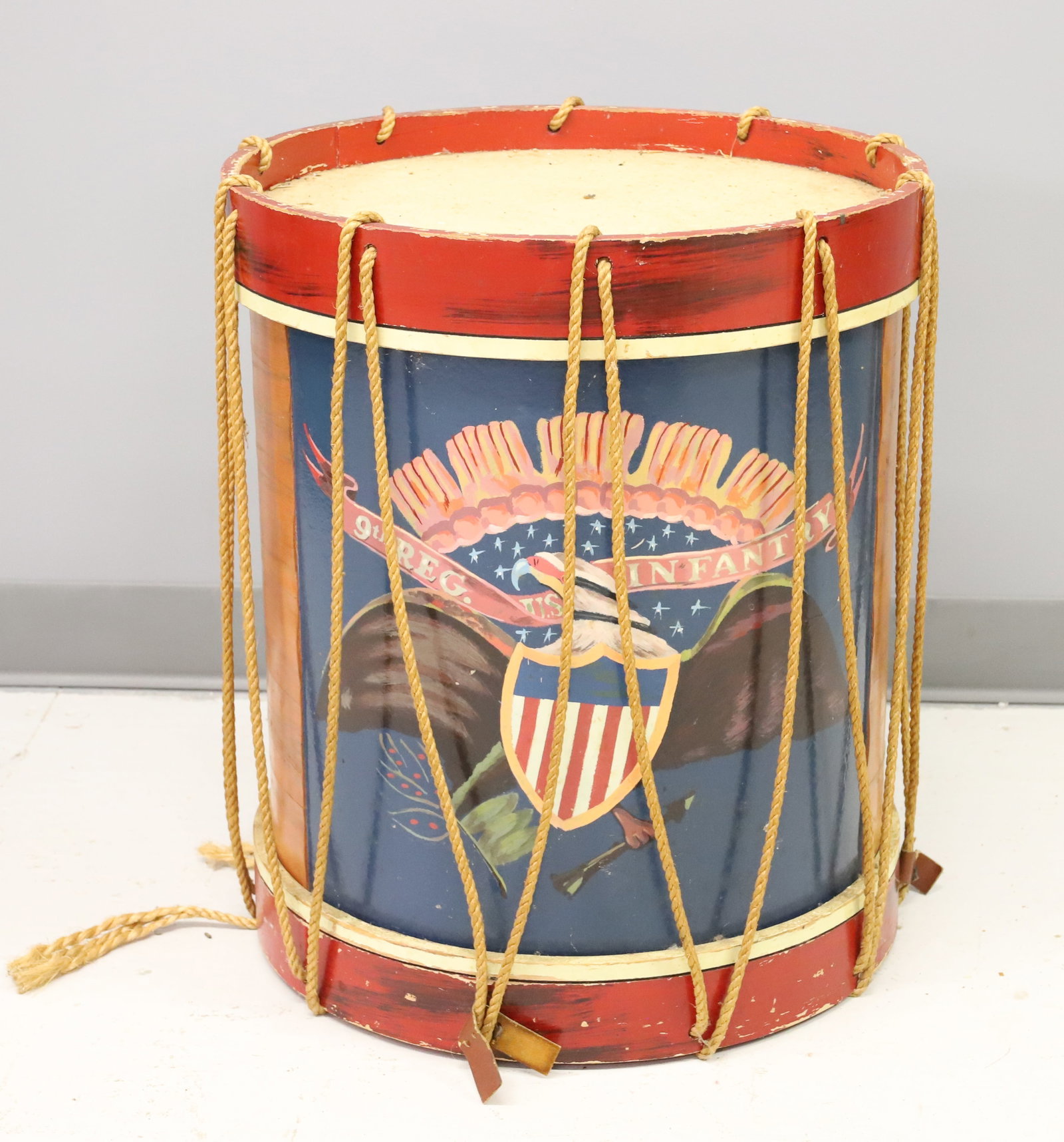 FOLK PAINTED DRUM SIDE TABLE: DRUM TABLE PAINTED WITH EAGLE/SHIELD "9TH REG. U.S. INFANTRY. SOLID TOP AND BOTTOM. 21 3/4" X 18 1/2". PLEASE READ CAREFULLY - ITEMS MUST BE PAID FOR THROUGH LIVE AUCTIONEERS OR WITH CASH OR CHECK IN
