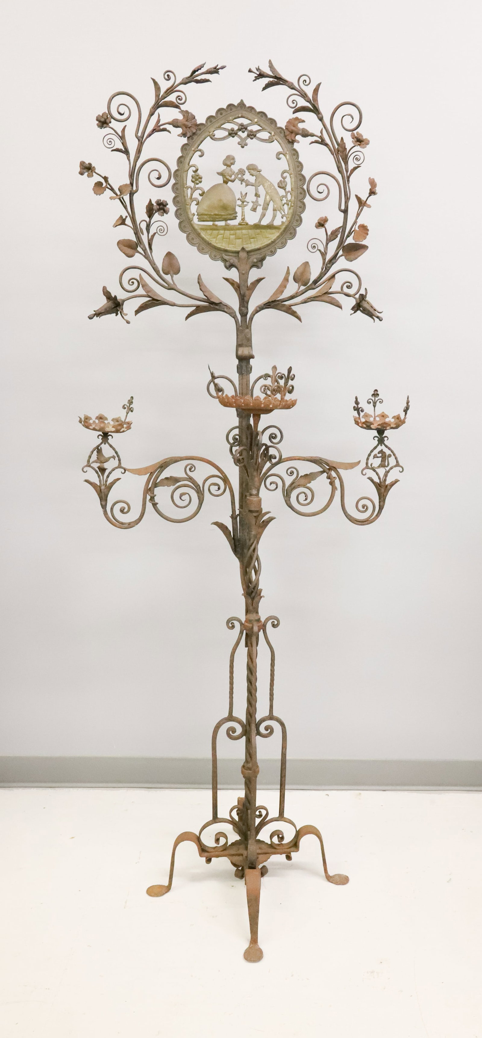 WROUGHT IRON / BRASS ELABORATE CANDLE HOLDER: CUT-BRASS COURTING SCENE AT TOP SURROUNDED BY IRON FLORAL AND LEAVES. (SLIDES INTO BASE) THREE SWING-ARM CANDLE HOLDERS WITH SQUIRREL AND BIRD MOTIF BELOW. 72" X 29". PLEASE READ CAREFULLY - ITEMS