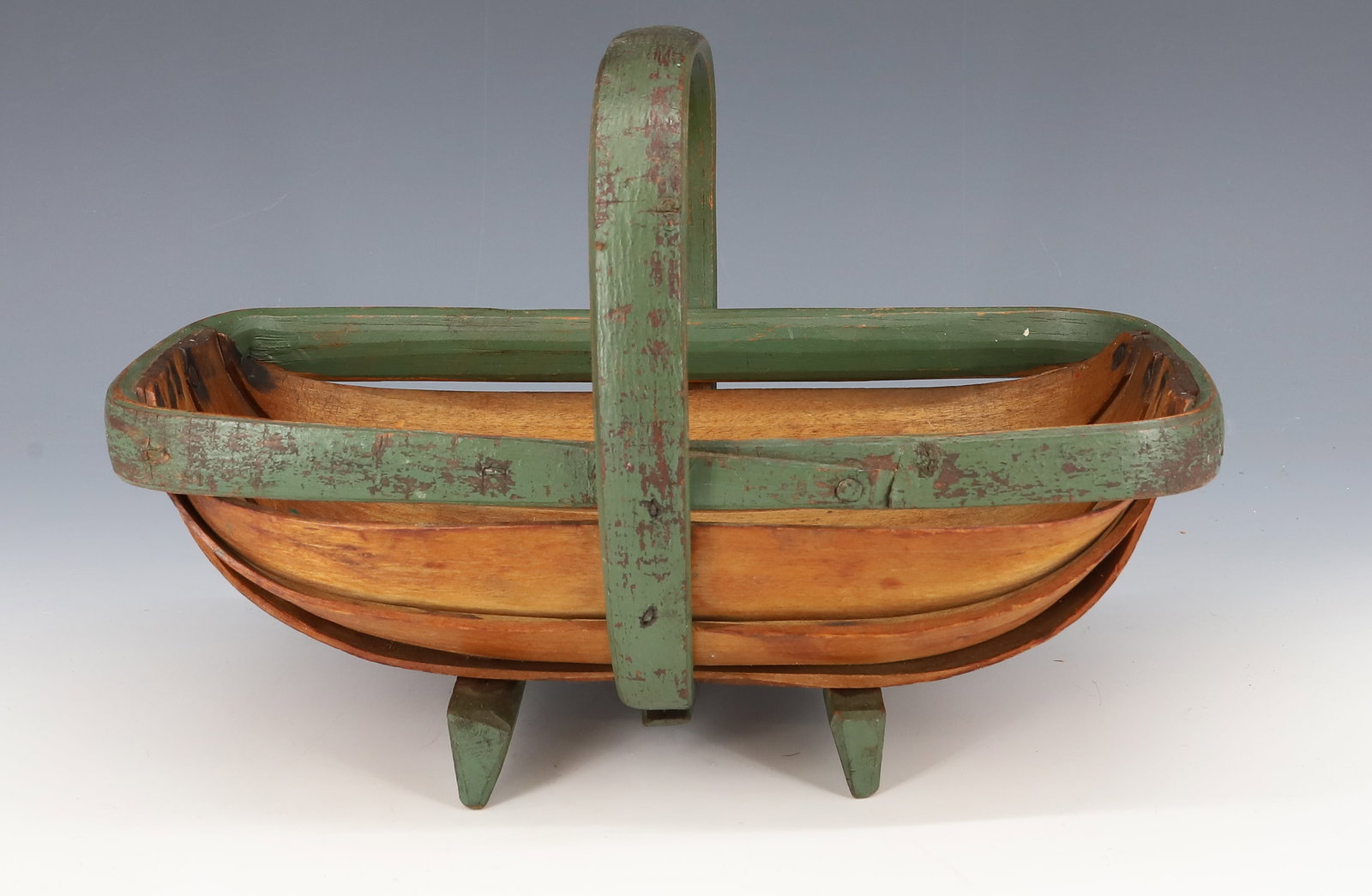 PAINTED TRUG BASKET: GATHER BASKET CONSTRUCTED OF STRIPS WITH GREEN PAINTED HANDLE, TRIM AND FEET. 10" L. PLEASE READ CAREFULLY - ITEMS MUST BE PAID FOR THROUGH LIVE AUCTIONEERS OR WITH CASH OR CHECK IN PERSON - Terms