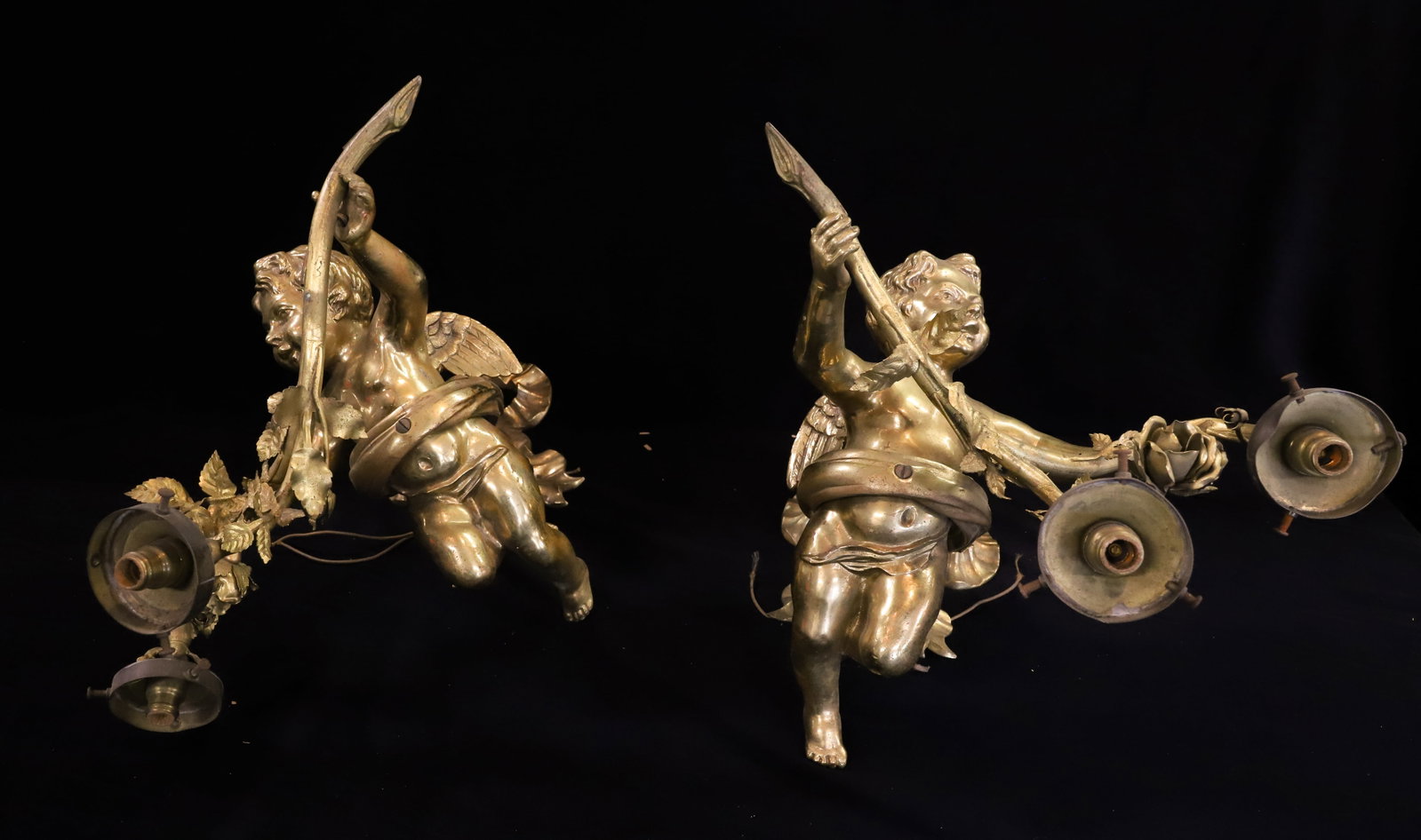 PAIR OF BRASS CHERUB WALL SCONCES: HEAVY BRASS CHERUBS HOLDING ROSE BRANCHES WITH TWO LIGHT SOCKETS. BACK PLATE IN SHAPE OF BOW. 12" X 12" X 13 1/4".