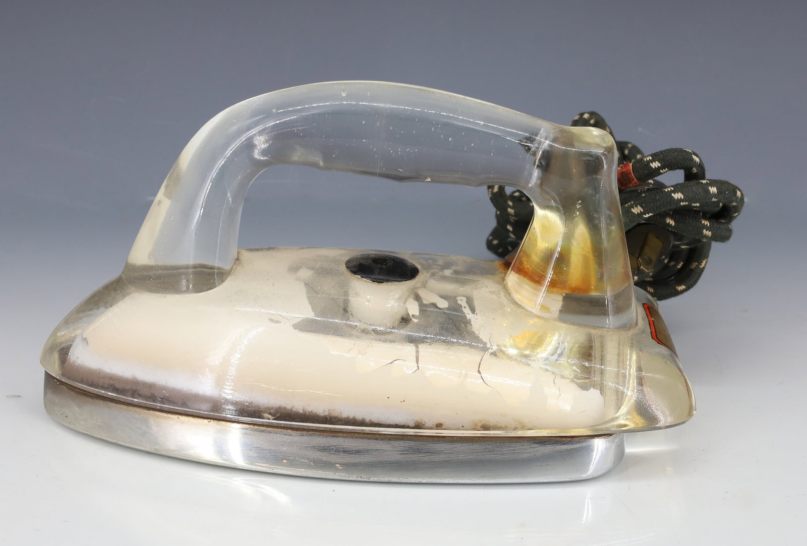 CLEAR GLASS ELECTRIC IRON: DETROIT APPLIANCE COMPANY. CLEAR WITH WHITE BACKGROUND. MEASURES 8 1/2" L. PLEASE READ CAREFULLY - ITEMS MUST BE PAID FOR THROUGH LIVE AUCTIONEERS OR WITH CASH OR CHECK IN PERSON - Terms for