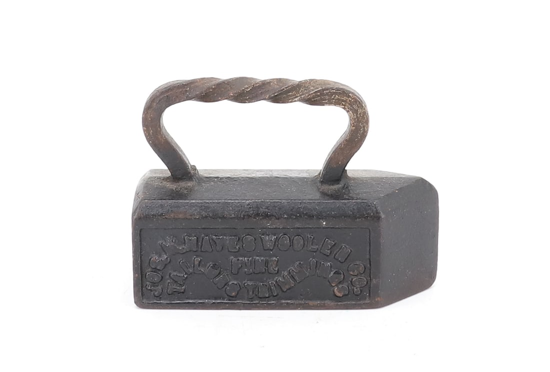 MINIATURE ADVERTISING TAILOR IRON PAPERWEIGHT: EMBOSSED "JOS. M. HAYES WOOLEN CO. FINE TAILORS TRIMMINGS". TWISTED HANDLE BLACK PAINTED SURFACE. 3 3/4" L. PLEASE READ CAREFULLY - ITEMS MUST BE PAID FOR THROUGH LIVE AUCTIONEERS OR WITH CASH OR CHEC