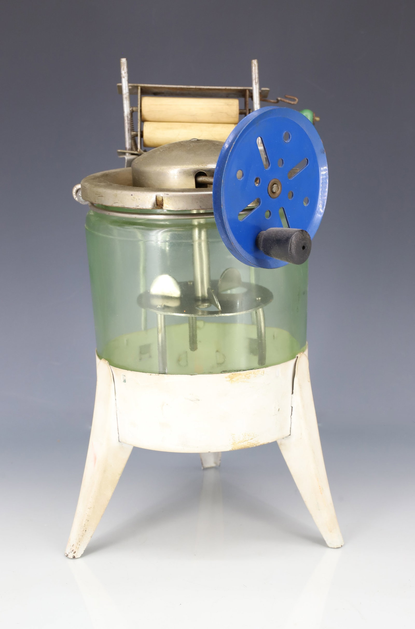 VINTAGE TOY WASHING MACHINE: GREEN DEPRESSION GLASS INSERT ON PAINTED METAL BASE. METAL CRANK AND WRINGER ATTACHED. 10 1/2" H. PLEASE READ CAREFULLY - ITEMS MUST BE PAID FOR THROUGH LIVE AUCTIONEERS OR WITH CASH OR CHECK IN PERSO