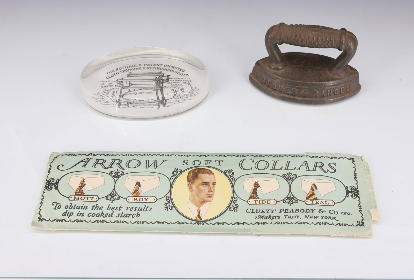 LOT OF LAUNDRY / STOVE ADVERTISING ITEMS: INCLUDING: "ROUND OAK STOVES & RANGES" SAD IRON. GLASS PAPERWEIGHT "THE ROTHHOLZ PATENT IMPROVED CLOTH SPONGING & REFINISHING SYSTEM...ROCHESTER, N.Y." 4 3/8" L. WITH, "ARROW SOFT COLLARS" ORIGINAL PA