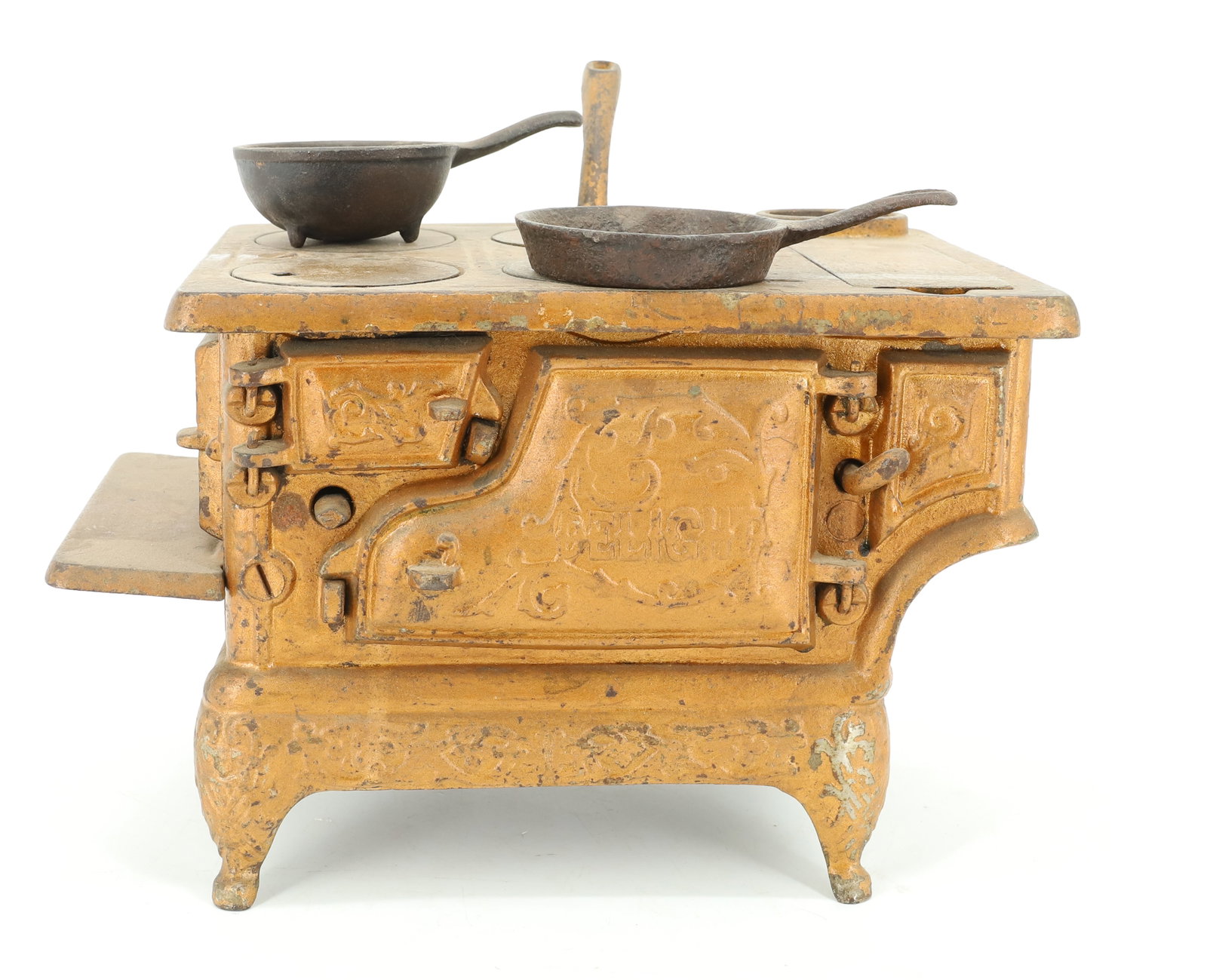 PAINTED CAST IRON TOY STOVE: GOLD PAINTED SURFACE, "DELIGHT" ON DOOR, INCLUDES; CAST IRON POT AND PAN - 6 1/4" X 9 1/2" X 6" PLEASE READ CAREFULLY - ITEMS MUST BE PAID FOR THROUGH LIVE AUCTIONEERS OR WITH CASH OR CHECK IN PERSON