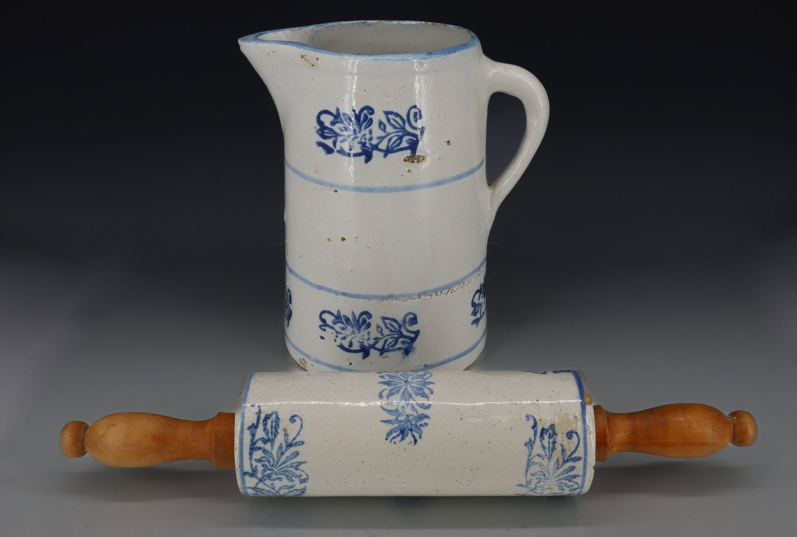 BLUE AND WHITE STONEWARE PITCHER AND ROLLING PIN: BLUE STENCILED WILD FLOWER PATTERN, PITCHER 8 3/4" AND ROLLING PIN WITH WOODEN HANDLES 15 1/4" L PLEASE READ CAREFULLY - ITEMS MUST BE PAID FOR THROUGH LIVE AUCTIONEERS OR WITH CASH OR CHECK IN PERSON