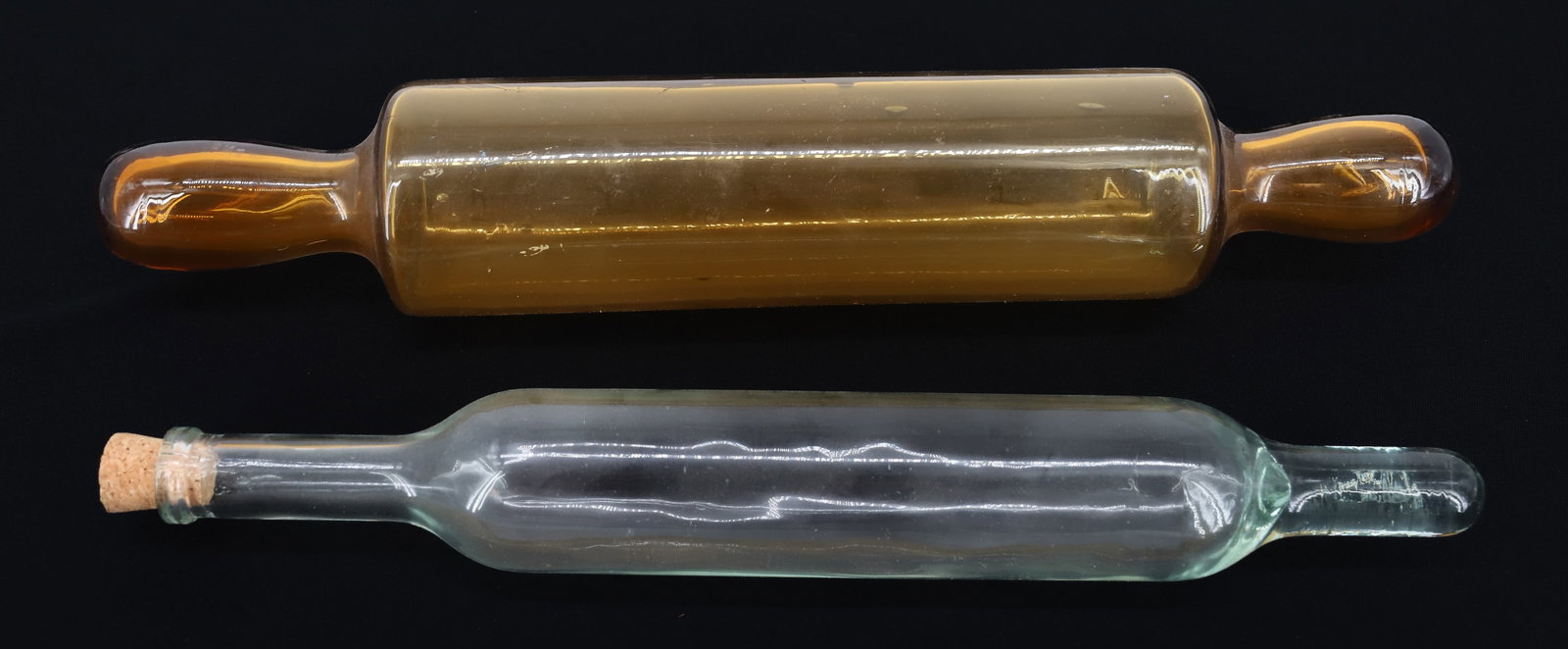 (2) BLOWN GLASS ROLLING PINS: CLEAR EXAMPLE WITH OPEN END AND CORK 13" L - WITH AMBER YELLOW EXAMPLE WITH ROUGH PONTIL ON END 14 3/4" PLEASE READ CAREFULLY - ITEMS MUST BE PAID FOR THROUGH LIVE AUCTIONEERS OR WITH CASH OR CHECK IN