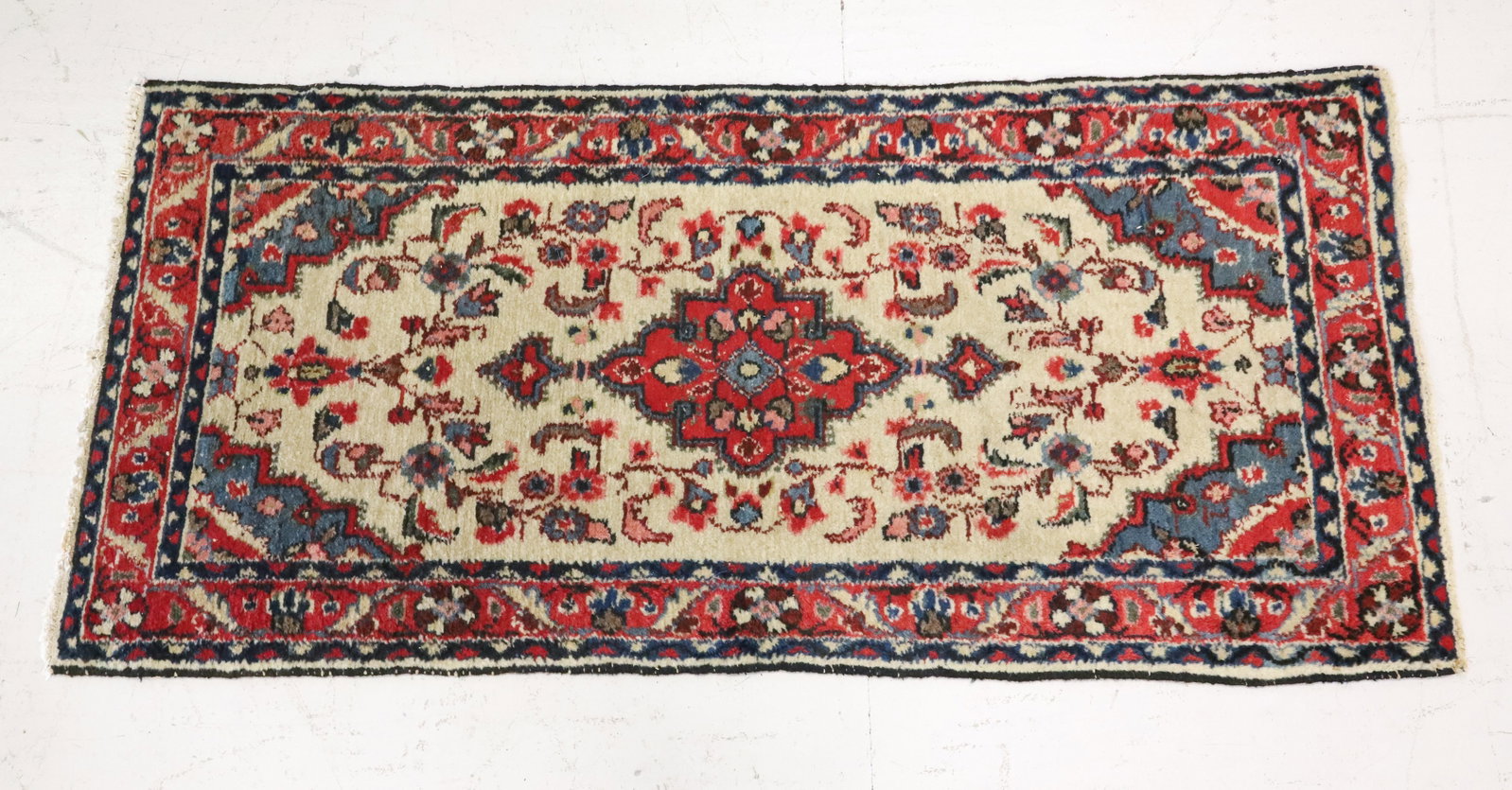 HANDWOVEN ORIENTAL RUG: WOOL WITH TAN / RED / BLUE / PINK FLORAL WITH MULTIPLE BORDERS. 57" X 26 1/4". PLEASE READ CAREFULLY - ITEMS MUST BE PAID FOR THROUGH LIVE AUCTIONEERS OR WITH CASH OR CHECK IN PERSON - Terms for