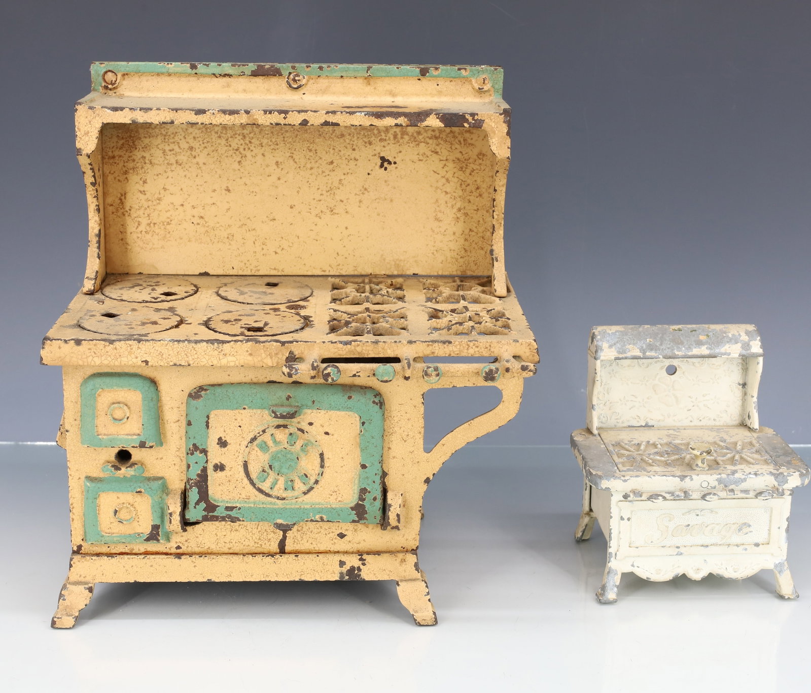 (2) CAST IRON TOY STOVES: INCLUDING: PAINTED ALUMINUM MINIATURE STOVE "AN ORIGINAL SAVAGE CALIFORNIA DESIGN" 4 1/4" X 4" X 3". WITH, "BLUE BIRD" YELLOW / GREEN PAINTED CAST IRON. 9" X 8" X 5". PLEASE READ CAREFULLY - ITEMS MUS