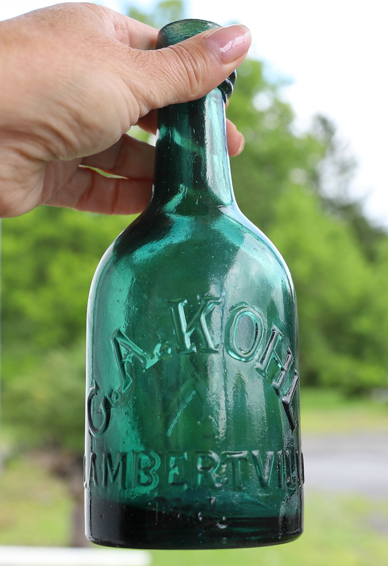 G.A. KOHL, LAMBERTVILLE, N.J. BOTTLE: GREEN BOTTLE WITH EMBOSSED NAME. LARGE "K" ON BACK. 7 1/4" H. PLEASE READ CAREFULLY - ITEMS MUST BE PAID FOR THROUGH LIVE AUCTIONEERS OR WITH CASH OR CHECK IN PERSON - Terms for Purchasing and