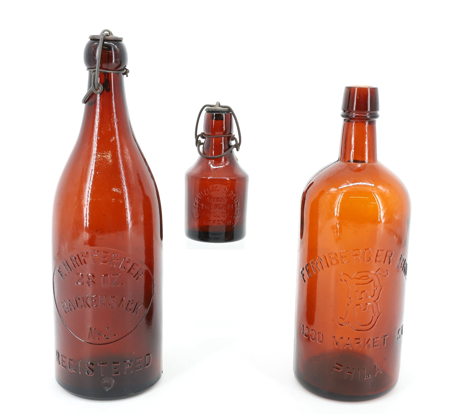 LOT OF AMBER BOTTLES: INCLUDING: F.H. RIPPERGER, HACKENSACK, N.J. 28 OZ. (11 1/2" H). FERNBERGER BROS. 1230 MARKET ST., PHILA. (10" H.) "VULCANIZING SOLUTION, M&M MFG. CO., AKRON, O." 5" H. PLEASE READ CAREFULLY - ITEMS MU