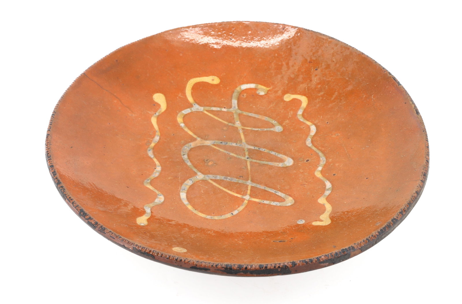 LARGE REDWARE POTTERY SLIP DECORATED PLATE: ORANGE GLAZE WITH YELLOW SLIP SQUIGGLE LINES. COGGLED EDGE. 13 1/8" D. PLEASE READ CAREFULLY - ITEMS MUST BE PAID FOR THROUGH LIVE AUCTIONEERS OR WITH CASH OR CHECK IN PERSON - Terms for Purchasing