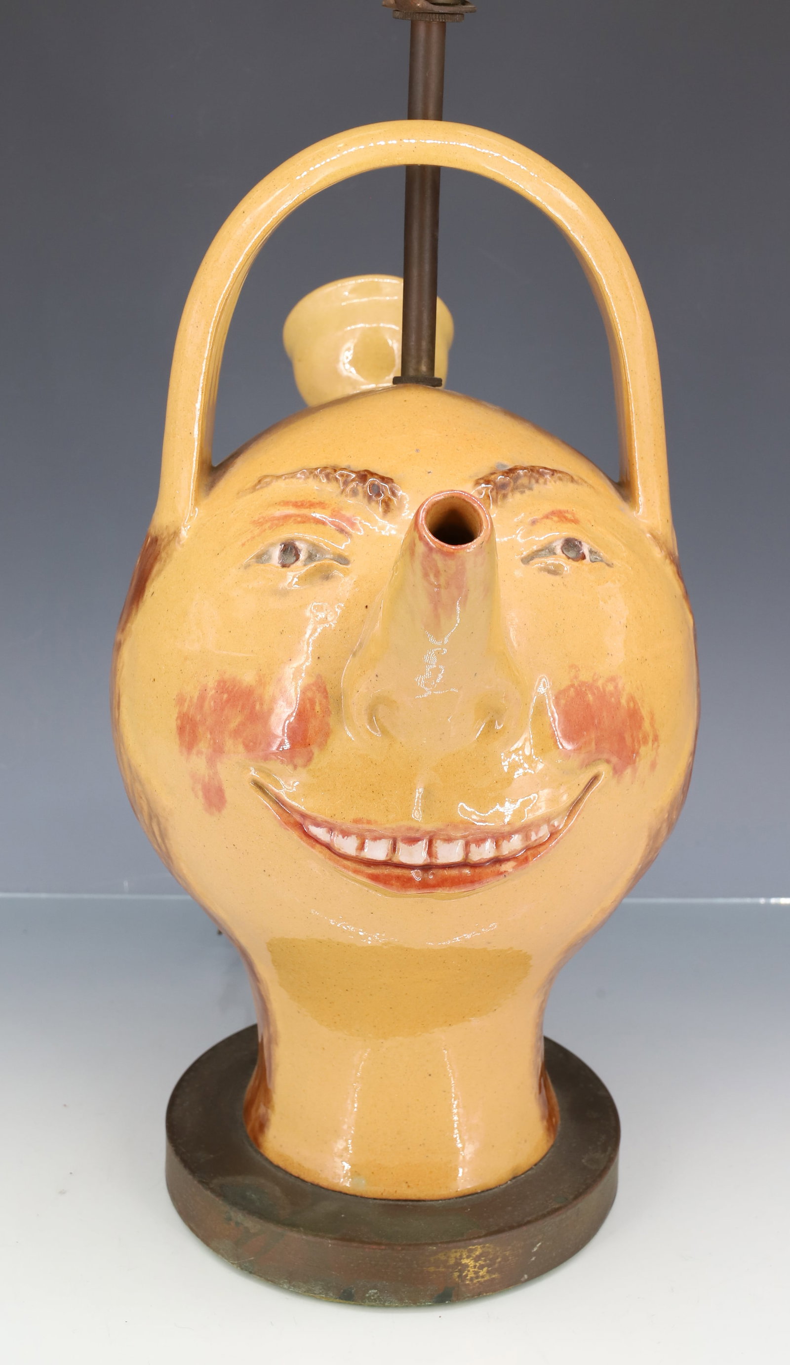 POTTERY FACE JUG LAMP: STYLE OF RAFAEL BORDALLO PINHEIRO. CONVERTED TO LAMP WITH ATTACHED BASE. NO MARKINGS. POT IS 12" H. PLEASE READ CAREFULLY - ITEMS MUST BE PAID FOR THROUGH LIVE AUCTIONEERS OR WITH CASH OR CHECK IN