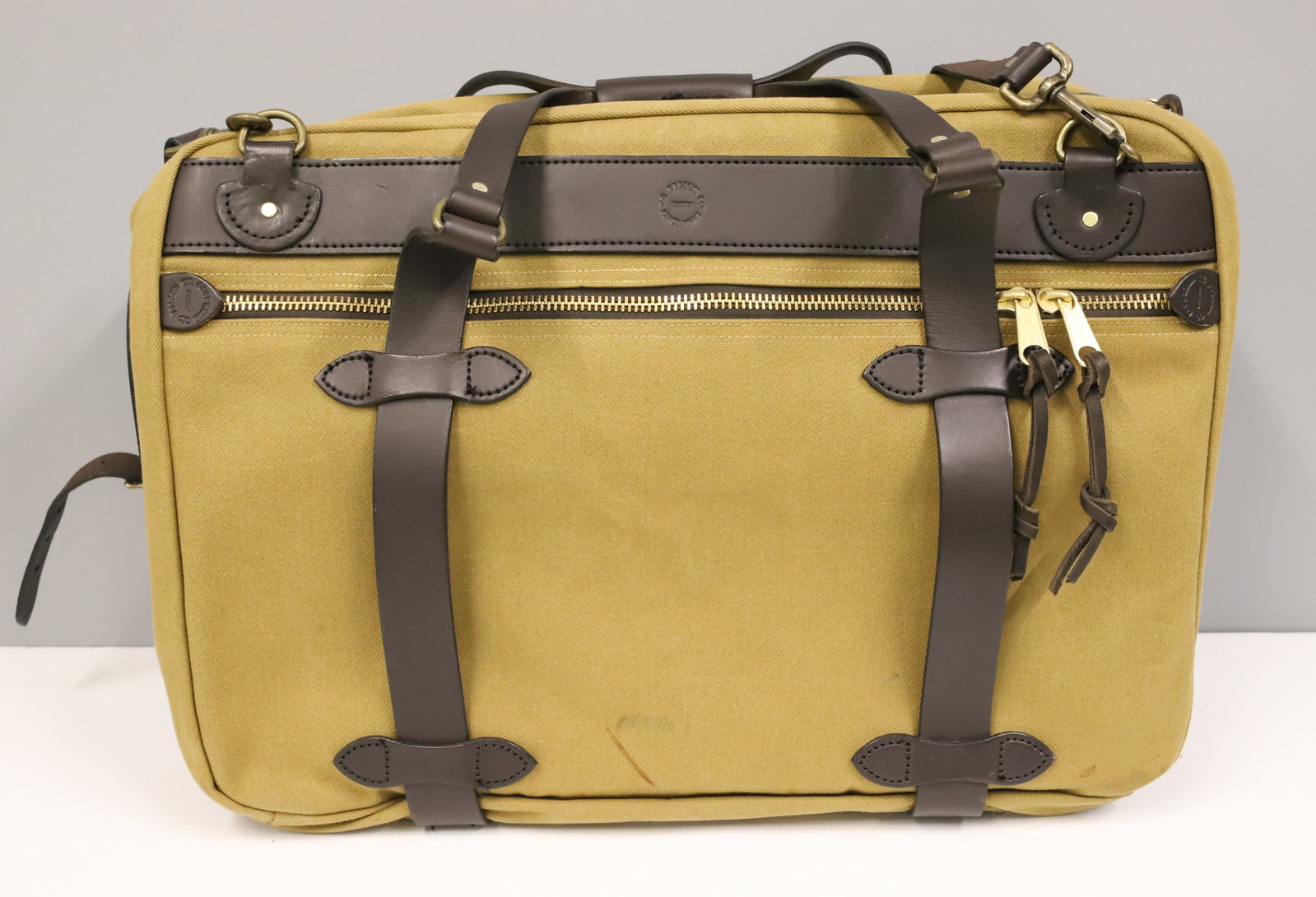 FILSON TWILL CANVAS PULLMAN DUFFEL BAG: TAN TWILL CANVAS. BRASS HARDWARE. LEATHER TRIM. 15" X 22". . PLEASE READ CAREFULLY - ITEMS MUST BE PAID FOR THROUGH LIVE AUCTIONEERS OR WITH CASH OR CHECK IN PERSON - Terms for Purchasing and