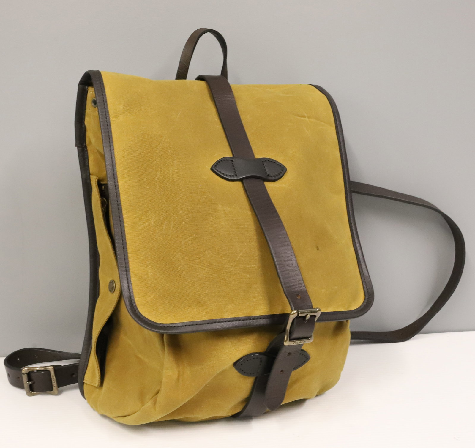 FILSON TIN CLOTH BACKPACK: CAMEL CANVAS WITH LEATHER STRAPS. QUILTED INTERIOR WITH SNAP POUCH. 17" X 13". PLEASE READ CAREFULLY - ITEMS MUST BE PAID FOR THROUGH LIVE AUCTIONEERS OR WITH CASH OR CHECK IN PERSON - Terms for