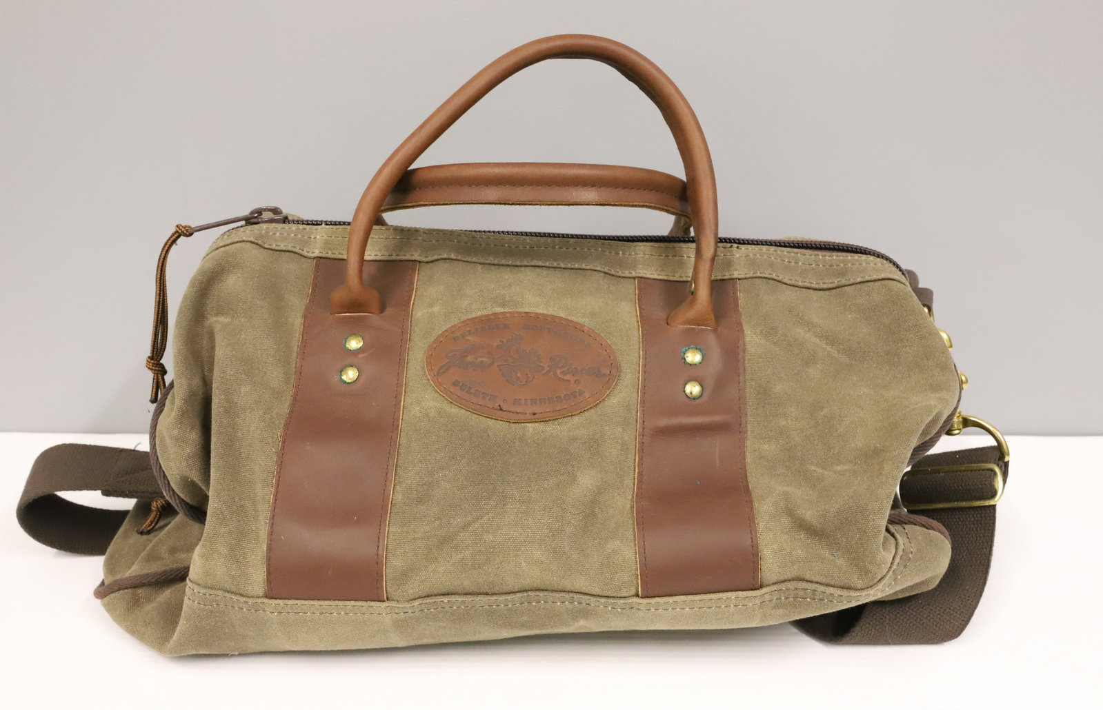 (2) DULUTH "FROST RIVER" BAGS: GREEN CANVAS DUFFLE BAGS WITH LEATHER TRIM AND HANDLES. WOVEN COTTON SHOULDER STRAPS. (9 1/2" X 19" AND 12 1/2" X 23") PLEASE READ CAREFULLY - ITEMS MUST BE PAID FOR THROUGH LIVE AUCTIONEERS OR WITH