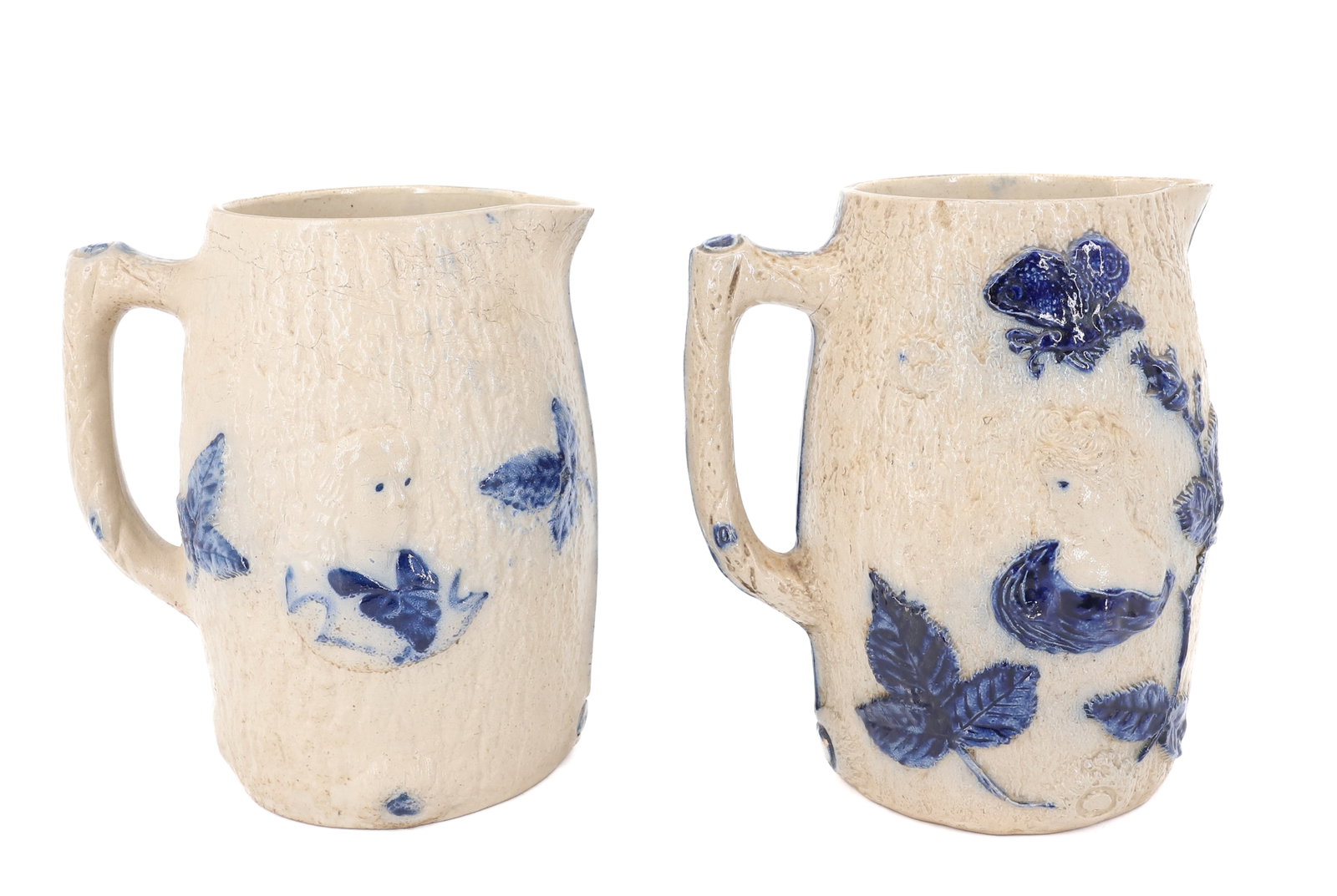 (2) WHITE'S UTICA STONEWARE PITCHERS: MOLDED FAUX-BARK WITH EMBOSSED FIGURE OF MAN AND WOMAN. BLUE HIGHLIGHTED LEAVES, FLOWERS AND BUTTERFLY. 8" H. PLEASE READ CAREFULLY - ITEMS MUST BE PAID FOR THROUGH LIVE AUCTIONEERS OR WITH CASH OR