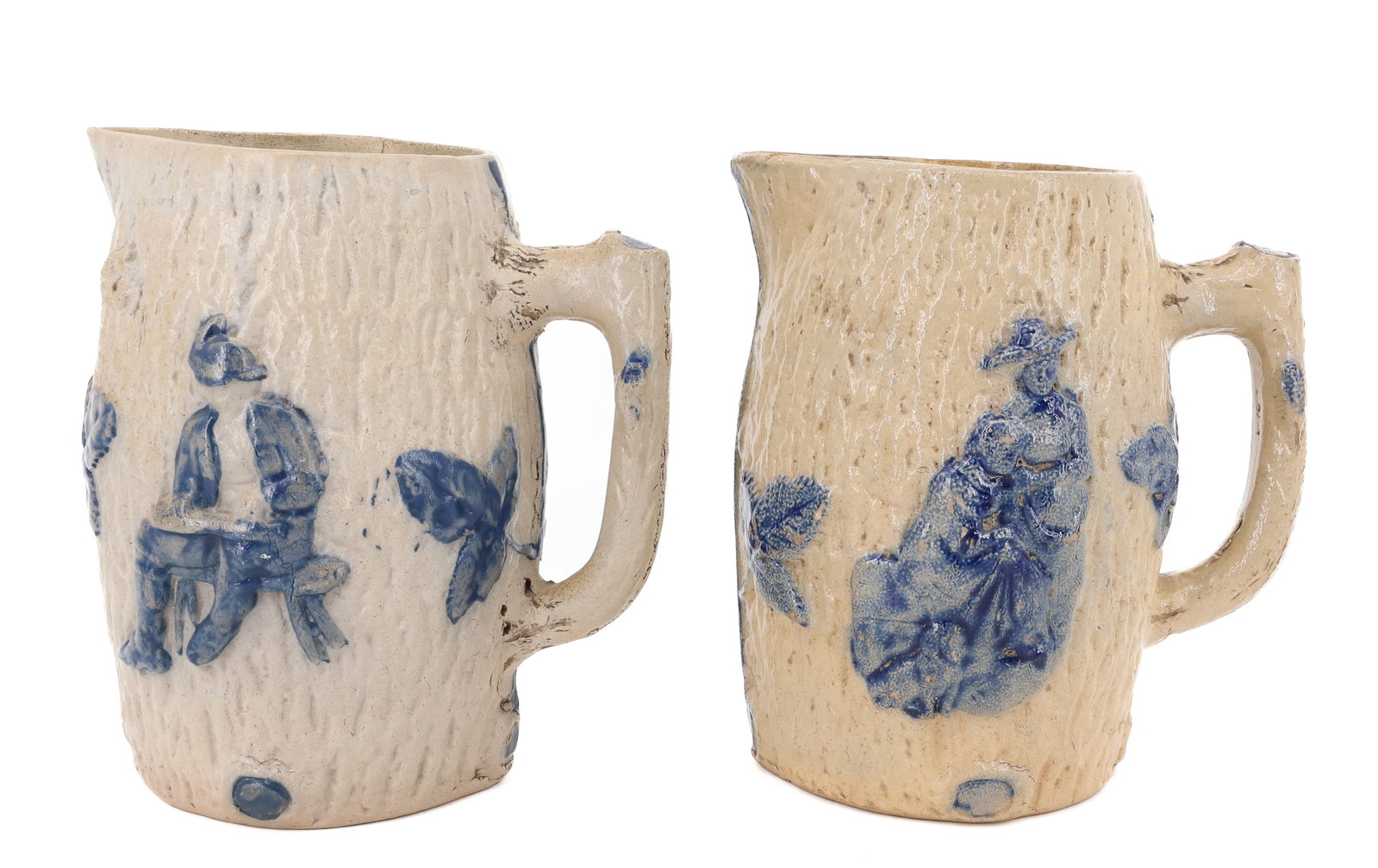 (2) WHITE'S UTICA STONEWARE PITCHERS: MOLDED FAUX-BARK. PEOPLE MOTIF ON EACH. BLUE HIGHLIGHTED LEAVES AND BUNCH OF GRAPES ON ONE PITCHER. 7 1/2" H. PLEASE READ CAREFULLY - ITEMS MUST BE PAID FOR THROUGH LIVE AUCTIONEERS OR WITH CASH OR