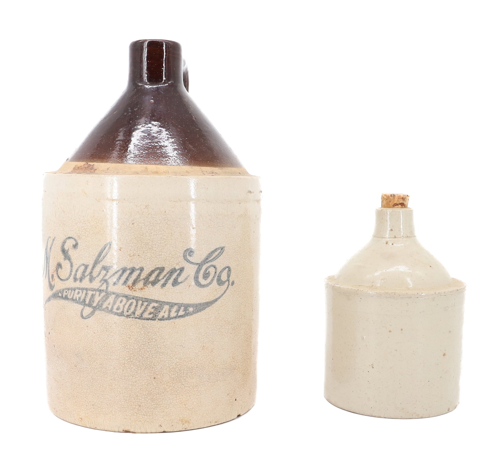 LOT OF (2) STONEWARE JUGS: "M. SALZMAN CO. PURITY ABOVE ALL" 11 3/4" H. SOLID WHITE MINI JUG 6 1/2" H. PLEASE READ CAREFULLY - ITEMS MUST BE PAID FOR THROUGH LIVE AUCTIONEERS OR WITH CASH OR CHECK IN PERSON - Terms for Purchasi
