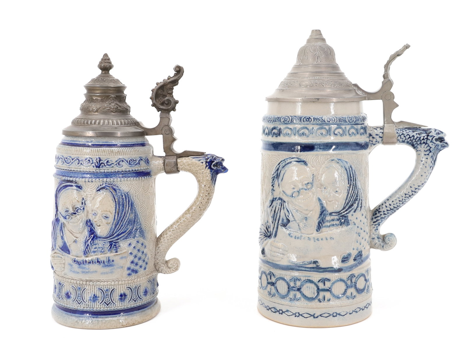 (2) WHITE'S UTICA STONEWARE STEINS: ELDERLY MAN / WOMAN READING THE NEWSPAPER. ALL OVER EMBOSSED DECORATION WITH BLUE. SEA SERPENT / DOLPHIN HANDLE. PEWTER LIDS. MRKD. 45 AND 46. 9 1/4" AND 10" HEIGHTS. STONEWARE IS 6 3/4" AND 7 3/4" HE