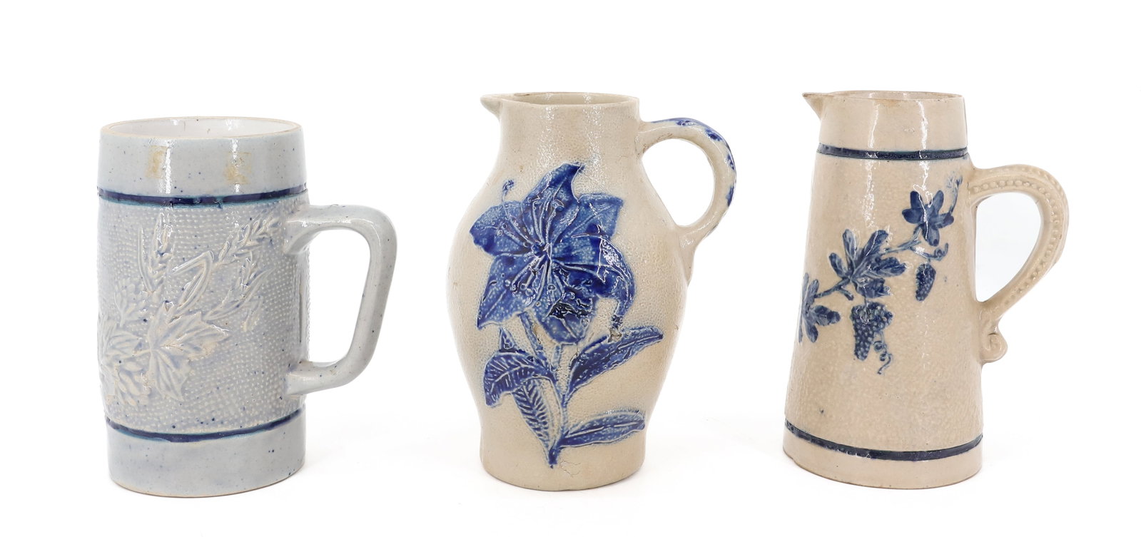 LOT OF WHITE'S UTICA STONEWARE PITCHERS / MUG: TWO EMBOSSED FLORAL SMALL PITCHERS 6 5/8" AND 6 1/2" HEIGHTS. MUG HAS LEAF/FLORAL DECORATION. MRKD. 5 ON BOTTOM. 5 7/8" H. PLEASE READ CAREFULLY - ITEMS MUST BE PAID FOR THROUGH LIVE AUCTIONEERS OR WI