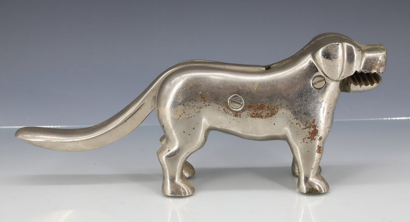 DOG NUTCRACKER IN NICKEL: HEAVY NUTCRACKER IN NICKEL FINISH. 11 1/2" L. PLEASE READ CAREFULLY - ITEMS MUST BE PAID FOR THROUGH LIVE AUCTIONEERS OR WITH CASH OR CHECK IN PERSON - Terms for Purchasing and Shipping of Auction Ite