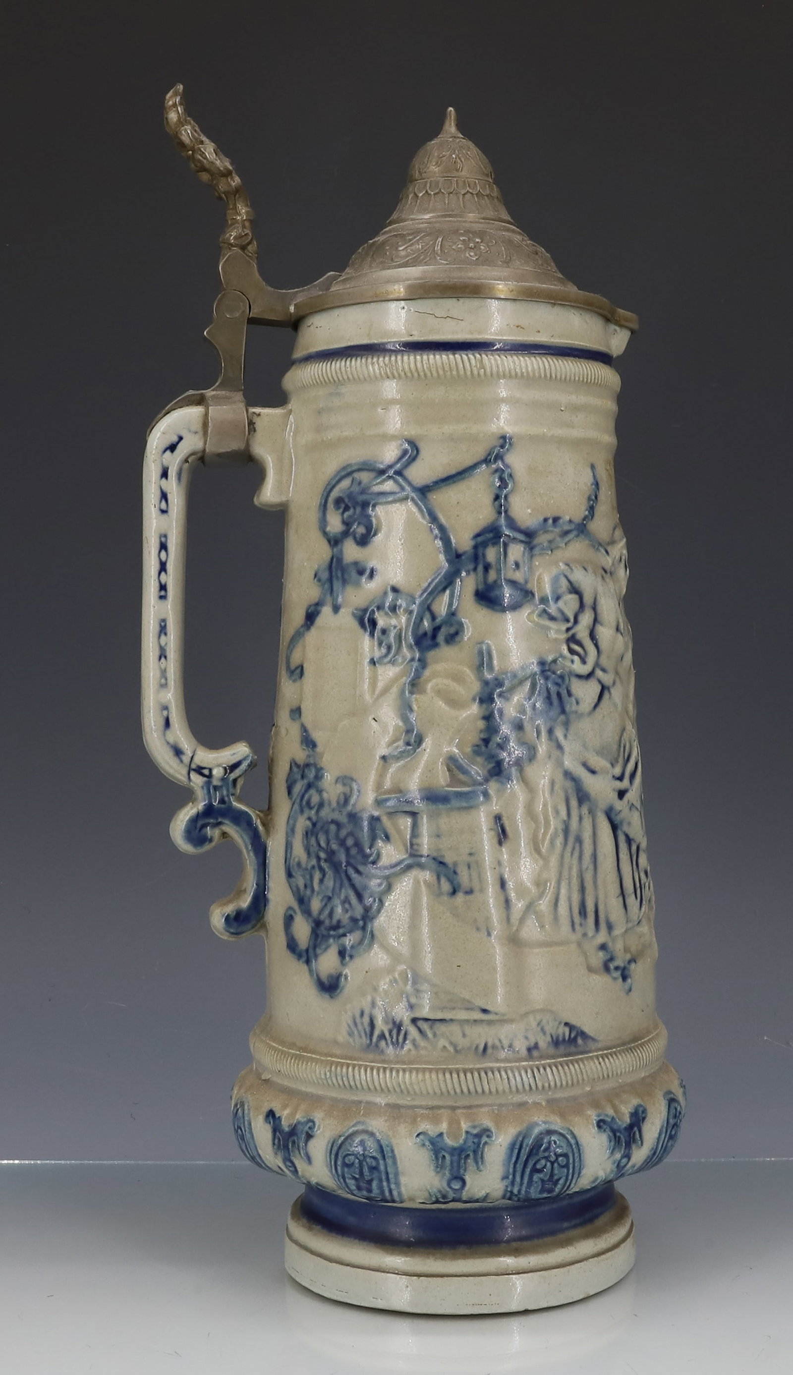 LARGE WHITE'S UTICA STONEWARE TANKARD, STEIN: EMBOSSED SCENE OF MAN / WOMAN. BLUE HIGHLIGHTED WITH PEWTER LID. 13" TOTAL HEIGHT. STEIN IS 10 3/4" H. PLEASE READ CAREFULLY - ITEMS MUST BE PAID FOR THROUGH LIVE AUCTIONEERS OR WITH CASH OR CHECK IN 