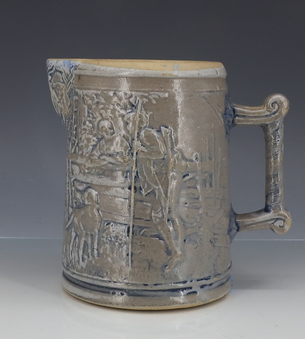WHITE'S UTICA STONEWARE MOLDED PITCHER: LIBERTY BELL MRKD. "BOY". OPPOSITE SIDE HAS HUNTER STANDING WITH DOG AT FENCE. BLUE HIGHLIGHTS. 6 3/4" H. PLEASE READ CAREFULLY - ITEMS MUST BE PAID FOR THROUGH LIVE AUCTIONEERS OR WITH CASH OR CHECK 