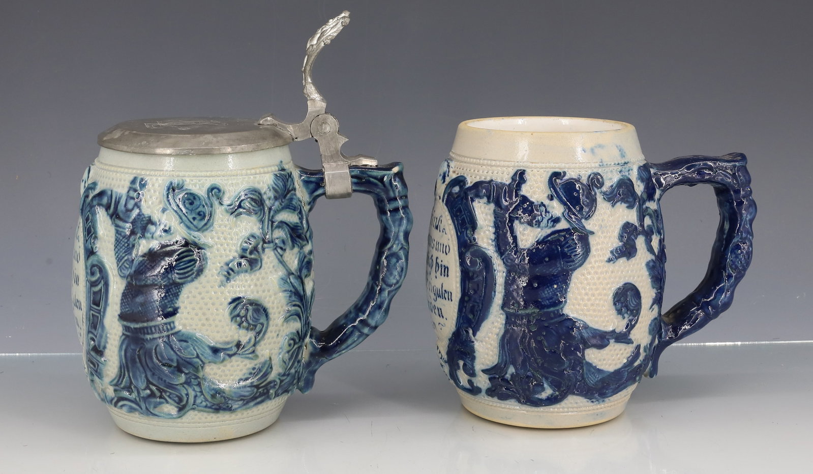 (2) WHITE'S UTICA STONEWARE MUGS, STEINS: DEPICTS SOLDIER IN ARMOR WITH VERSE. ONE HAS PEWTER LID WITH INSCRIPTION. 5" H. PLEASE READ CAREFULLY - ITEMS MUST BE PAID FOR THROUGH LIVE AUCTIONEERS OR WITH CASH OR CHECK IN PERSON - Terms for Purc