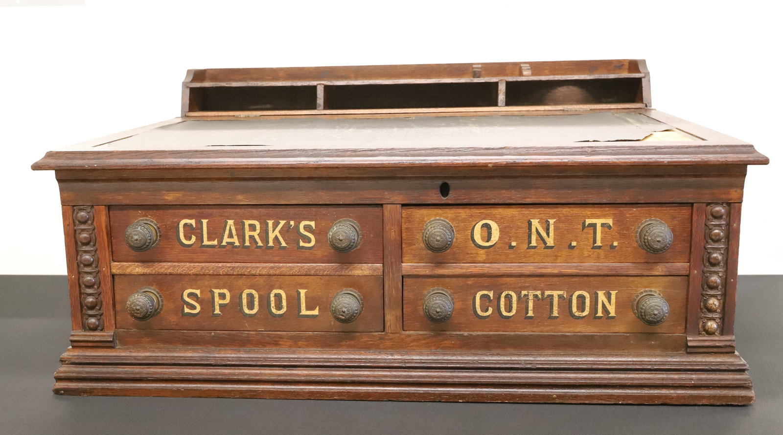 CLARK'S SPOOL CABINET / DESK: FOUR DRAWERS UNDER SLANT-TOP LIFT-LID. MRKD. "CLARK'S, O.N.T. SPOOL COTTON". 15" X 29" X 21". PLEASE READ CAREFULLY - ITEMS MUST BE PAID FOR THROUGH LIVE AUCTIONEERS OR WITH CASH OR CHECK IN PERSON - 